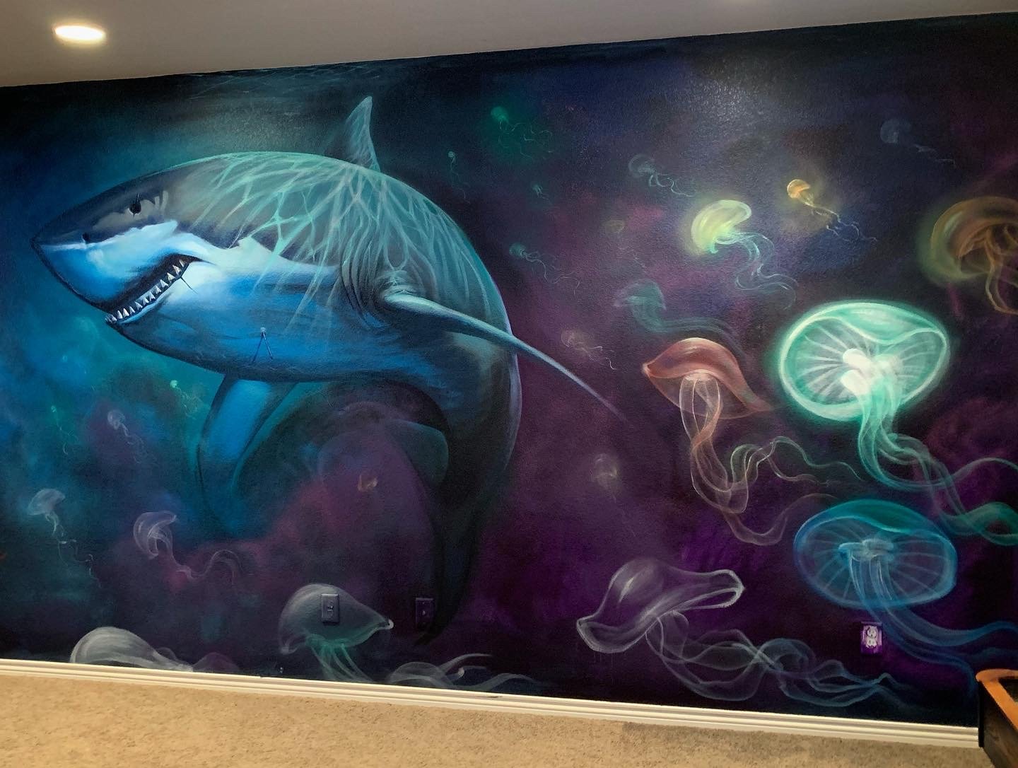 Colorful mural of a great white shark swimming in the ocean surrounded by glowing jellyfish and aquatic creatures.