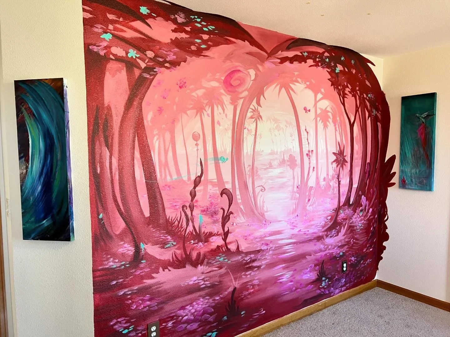 A large pink and purple mural depicting a whimsical forest scene with trees, a winding river, and foliage, flanked by two smaller abstract paintings on each side.