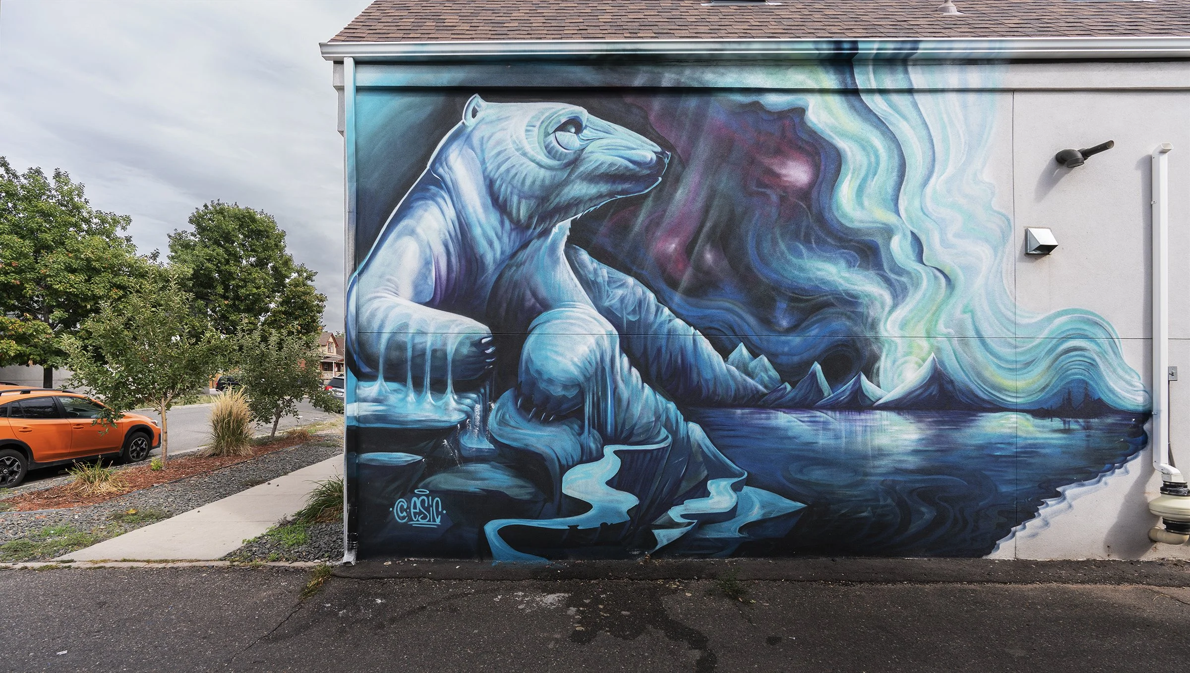 A vibrant mural on a building wall depicting a large, stylized seahorse in shades of blue with swirling water and mountain landscape in the background.