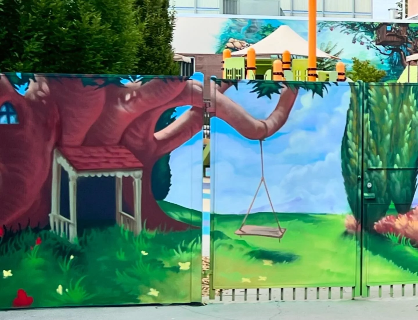 Colorful mural depicting a treehouse, a swing hanging from a tree branch, and vibrant greenery in a park setting.