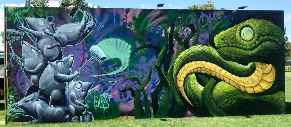Colorful graffiti mural featuring mice with spray paint on the left and a large green chameleon on the right.