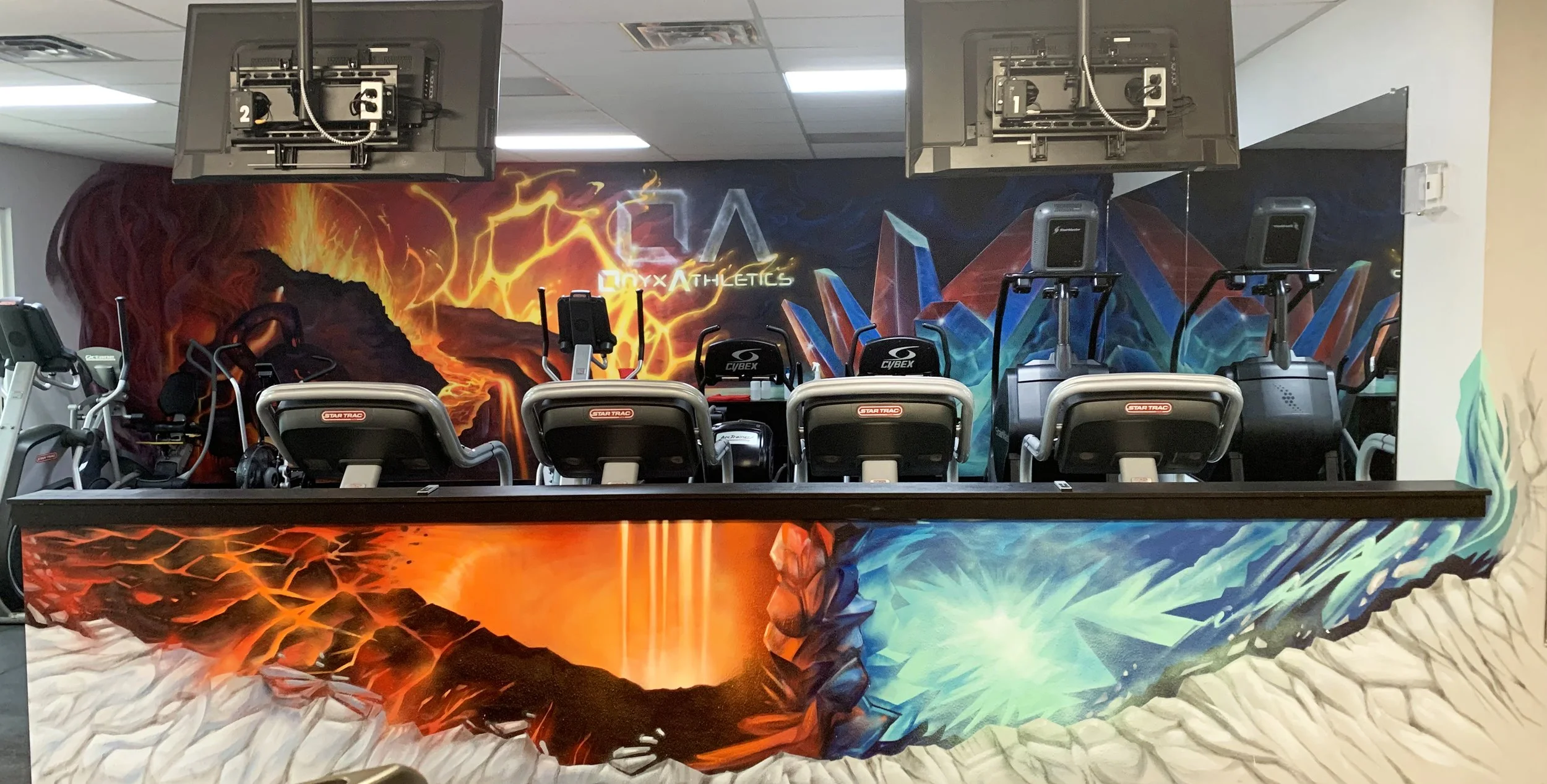 Fitness area with colorful wall art featuring volcanoes, ice crystals, and abstract patterns, and exercise machines including treadmills and ellipticals.