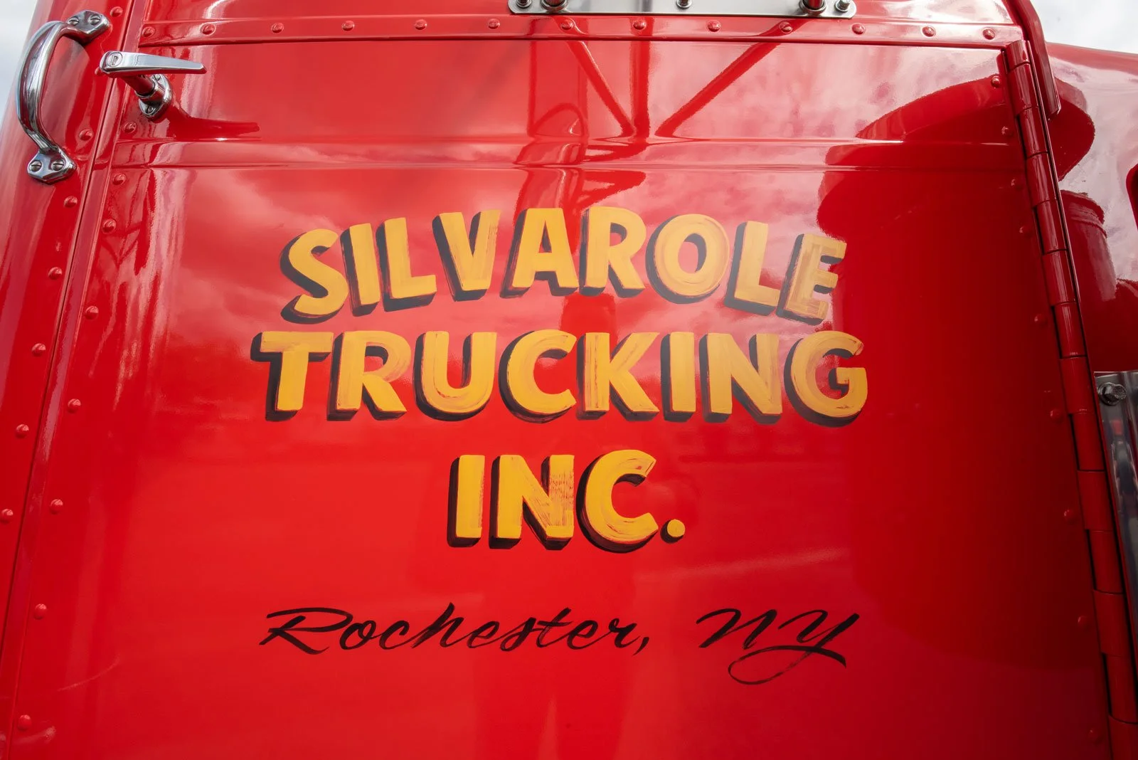 Red truck with yellow and black lettering that reads 'SILVAROLE TRUCKING INC.' and black cursive text below that reads 'Rochester, NY'.