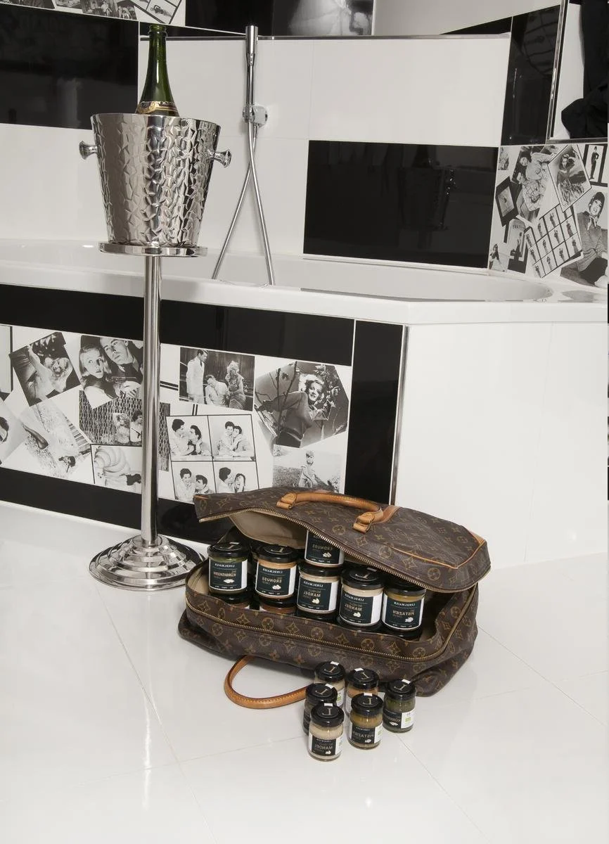 Bild im Bad mit einer Badewanne im Editorial-Stil, davor ein Leder-Koffer gefüllt mit Nuss-Cremes.