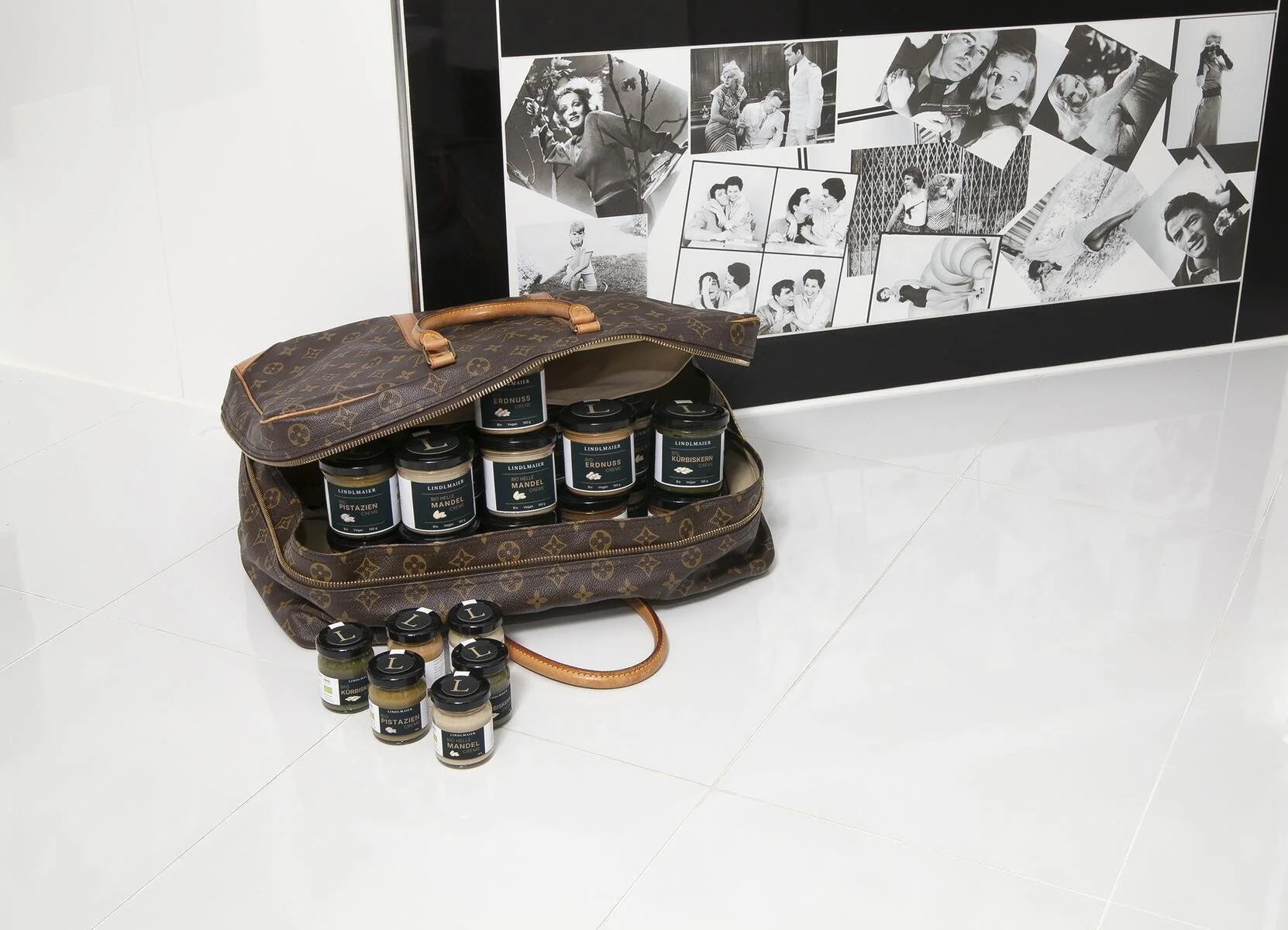 Nahaufnahme eines Leder-Koffers gefüllt mit Nuss-Cremes, vor einer Badewanne mit Fliessen aus Filmszenen.