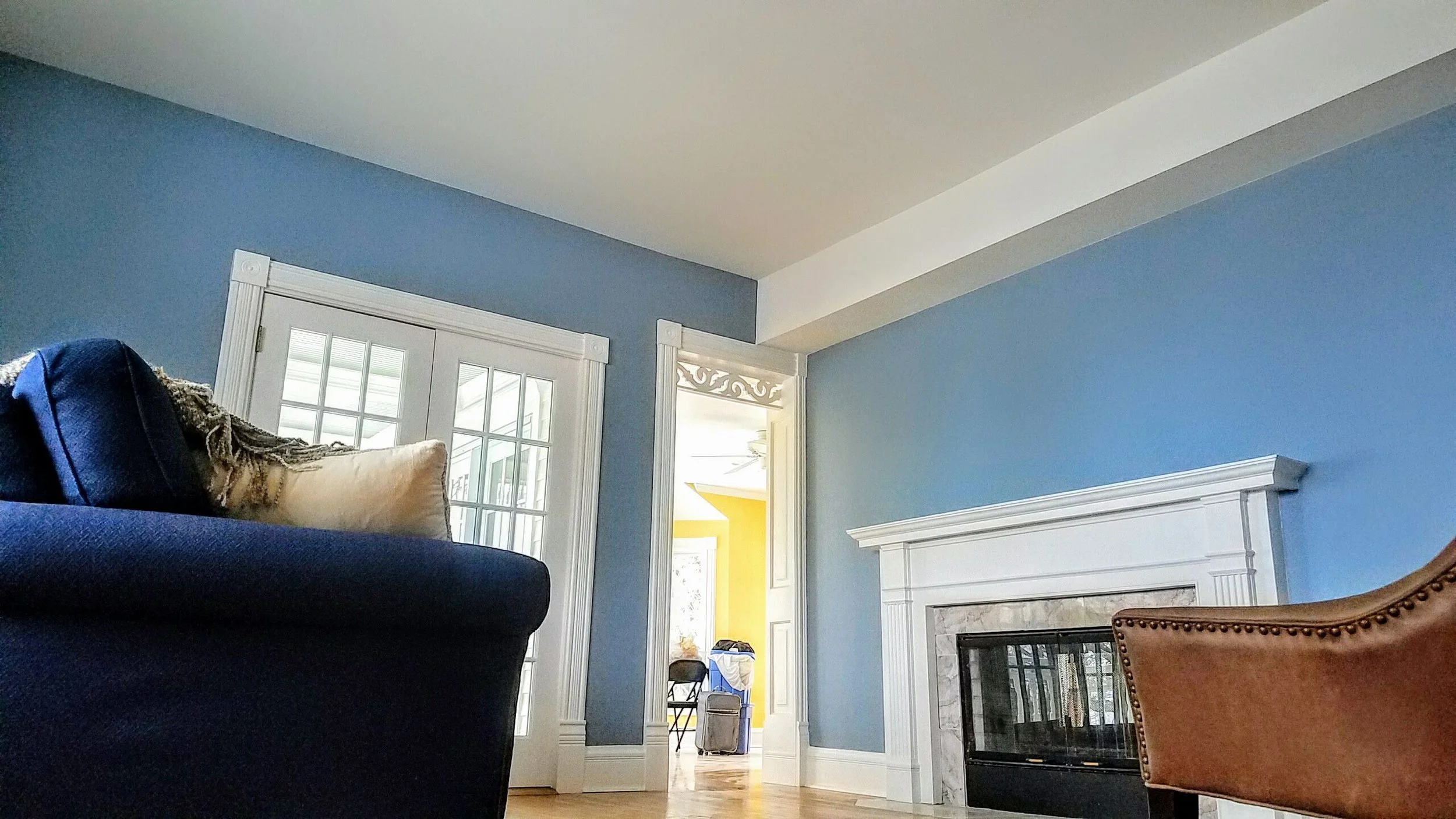 Living room with blue walls, white framed glass doors, white mantel fireplace, and brown leather chair.