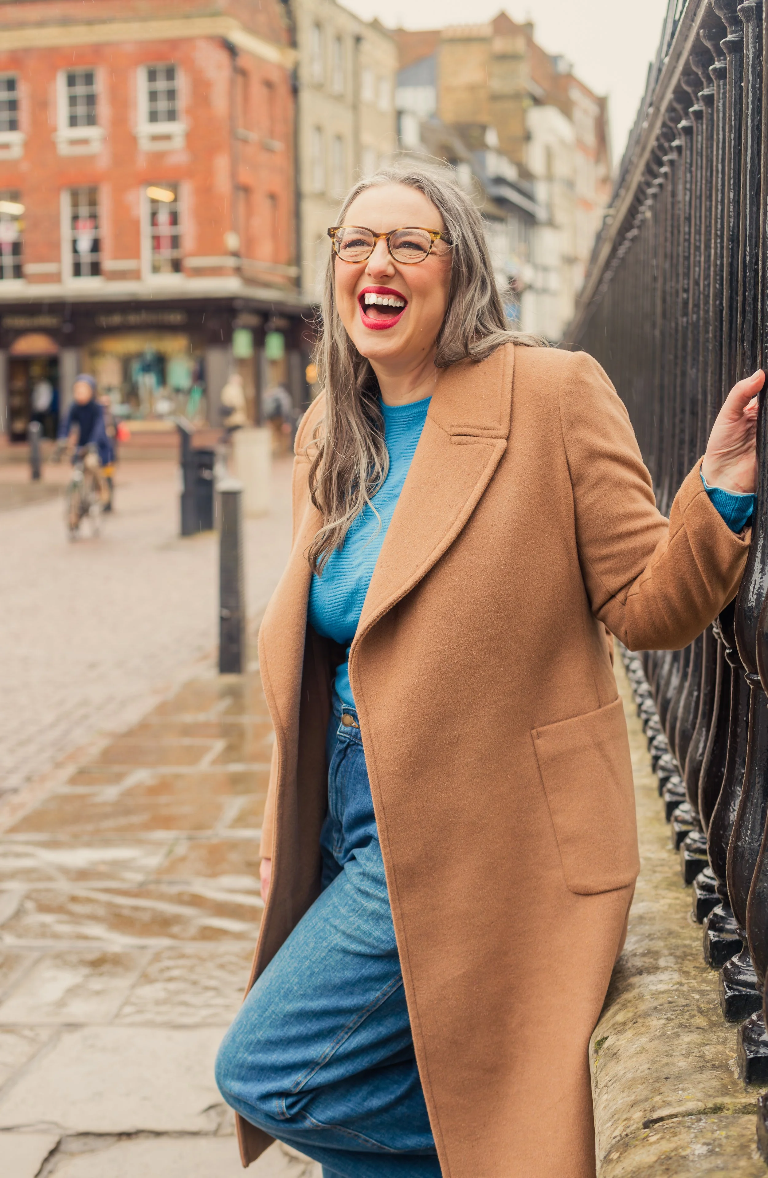 Photo of woman in the street wearing a brown coat laughing
