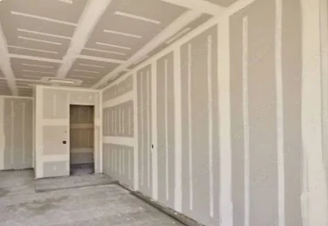 Empty unfinished garage with drywall and exposed concrete floor.
