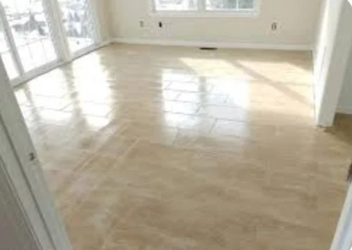 Empty room with light-colored wooden flooring, white walls, and large windows letting in natural light.