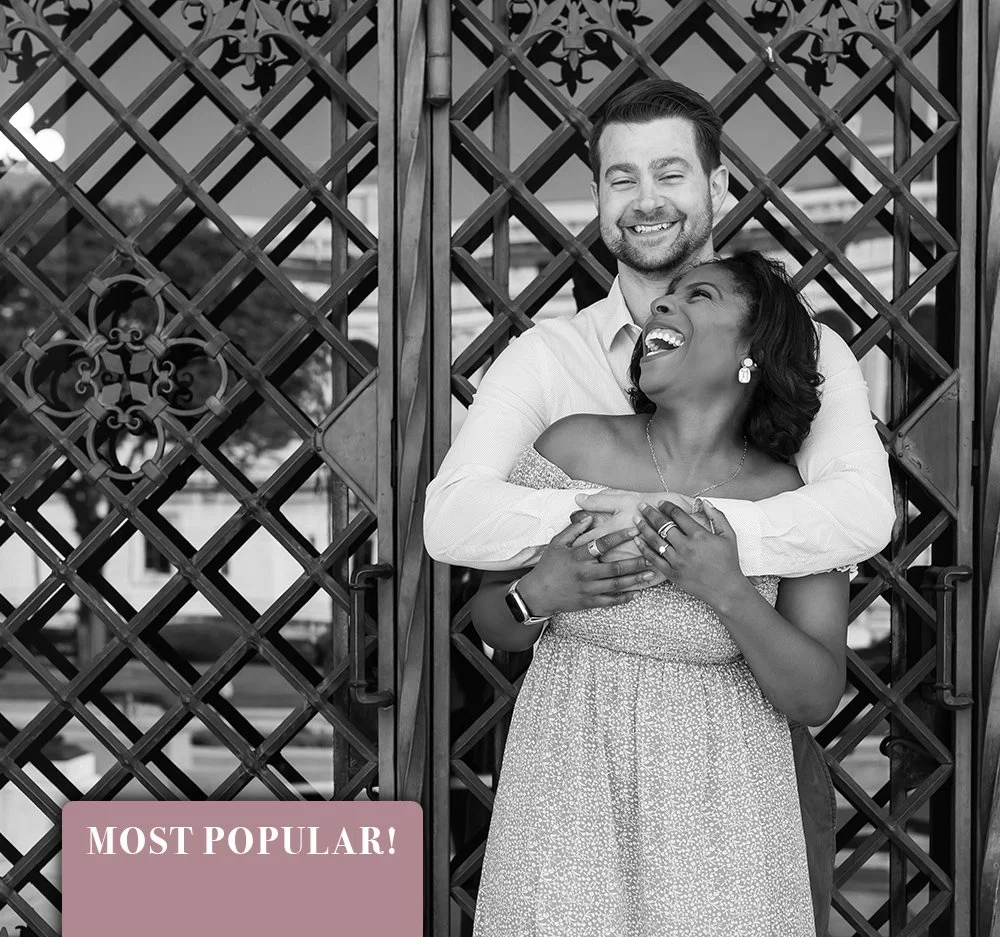 A happy couple, a man and a woman, sharing a joyful embrace and laughing together in front of a decorative wooden gate. The woman is wearing a dress and jewelry, and the man is in a light-colored shirt. Engagement photos at DIA in Detroit