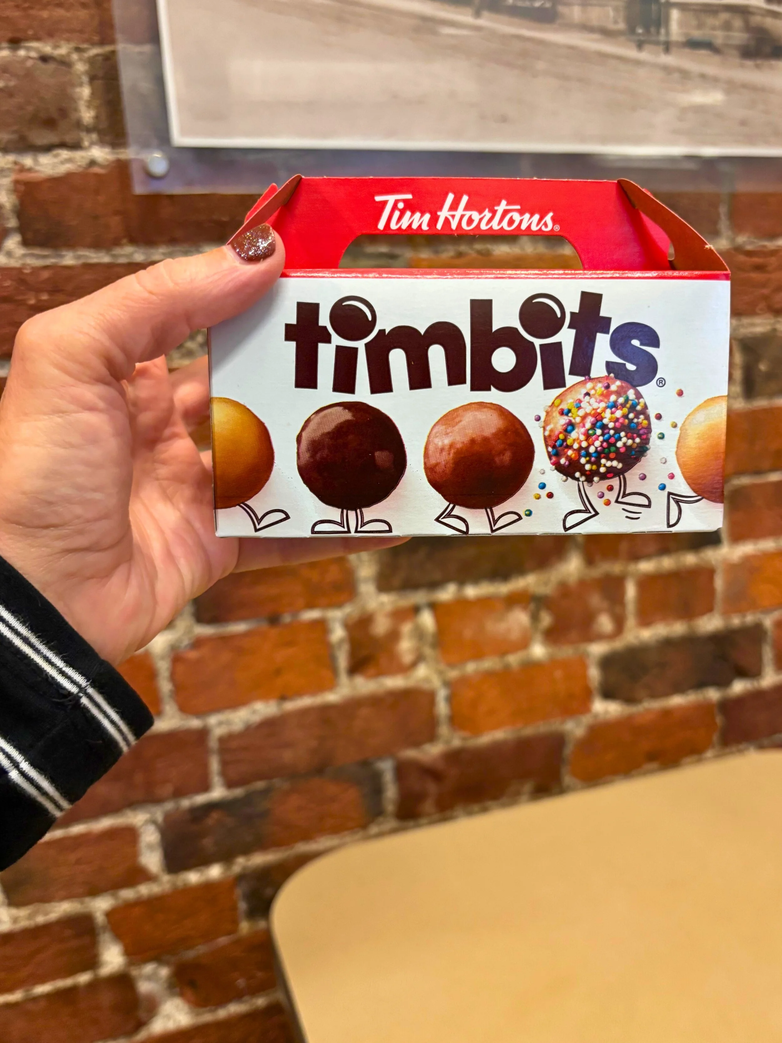 Maggie is holding a box of timbits in a Tim Hortons in St John, New Brunswick.