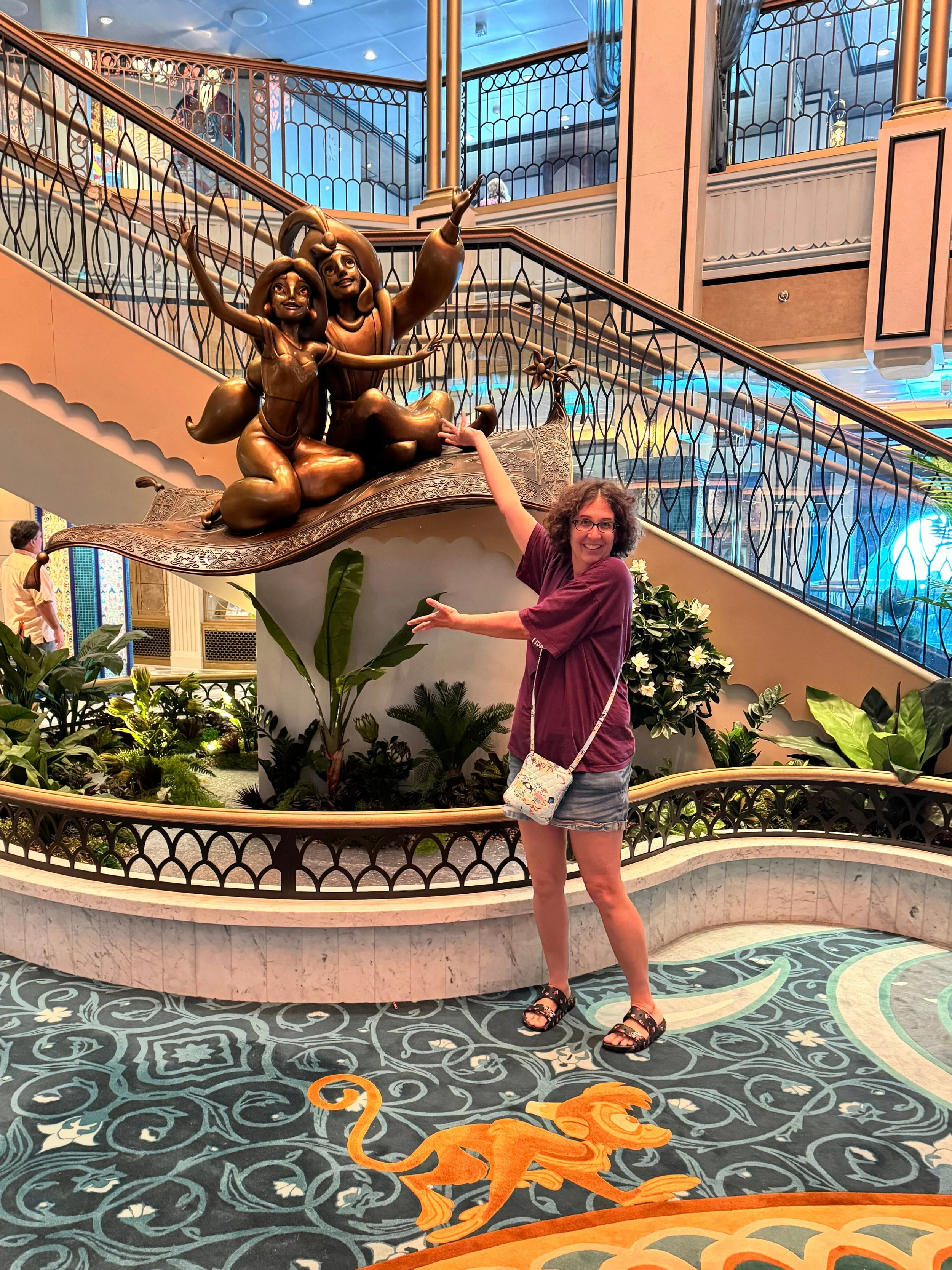 On The Disney Treasure, Maggie is gesturing to the statue of Jasmine and Aladdin in the Grand Hall.