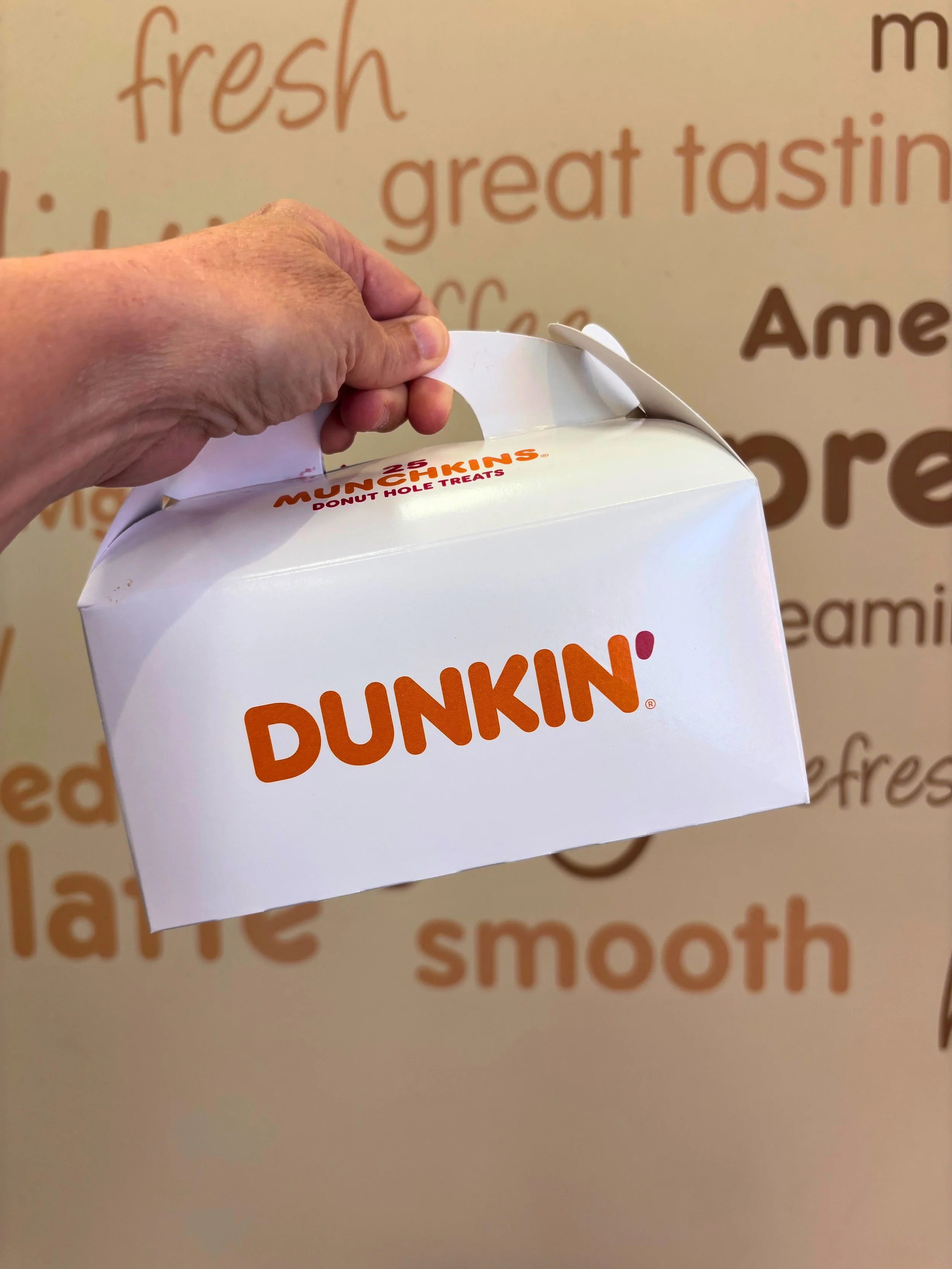 Maggie holding .a box of munchkins from Dunkin