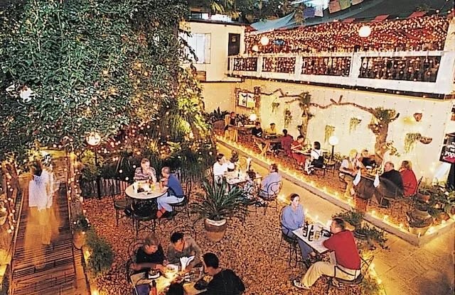 Garden dining courtyard at Kilroys of Kathmandu restaurant at night with candlelit tables and guests enjoying dinner under trees