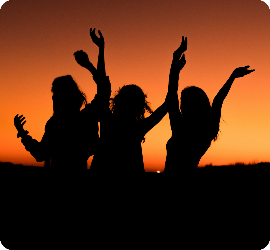 Silhouettes of three women dancing during sunset.