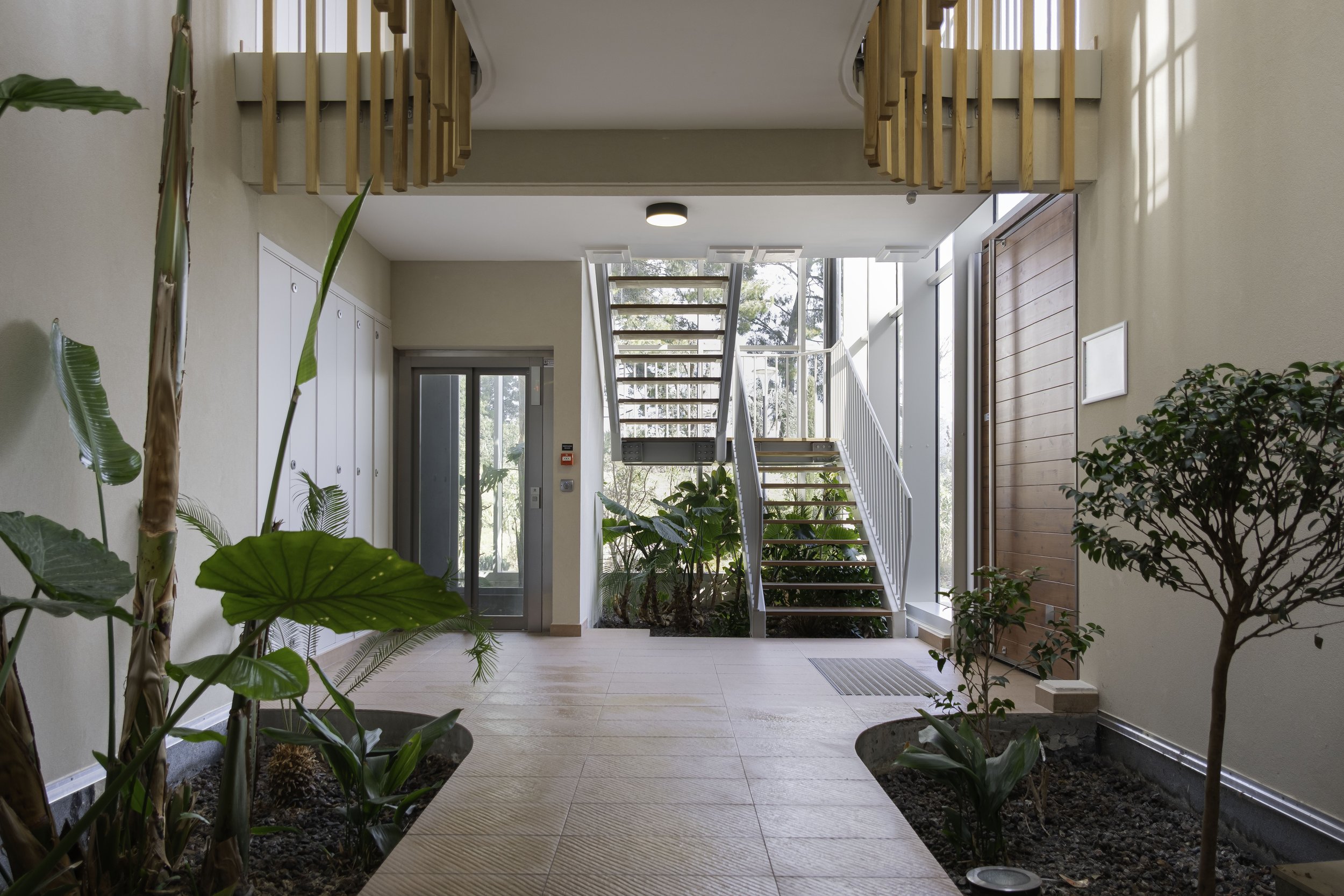 Photographie immobilière mettant en avant les parties communes avec accès à l'ascenseur et aux escaliers. 