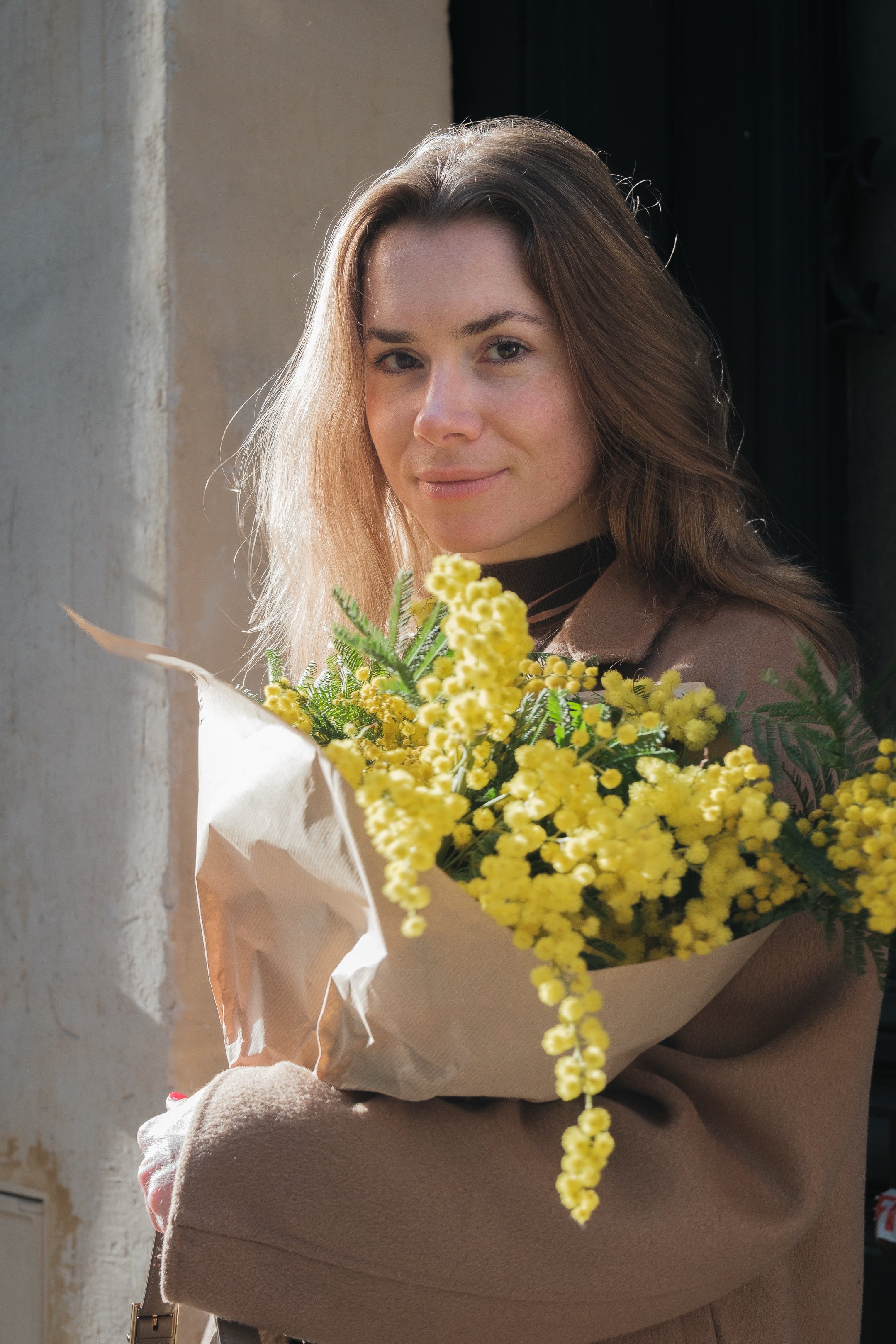 Photographie prise dans les rues de Paris montrant les détails des conditions extérieures (luminosité forte, ombres) et la palette de couleurs harmonieuse. Le mimosa apporte de la douceur à la mannequin. 