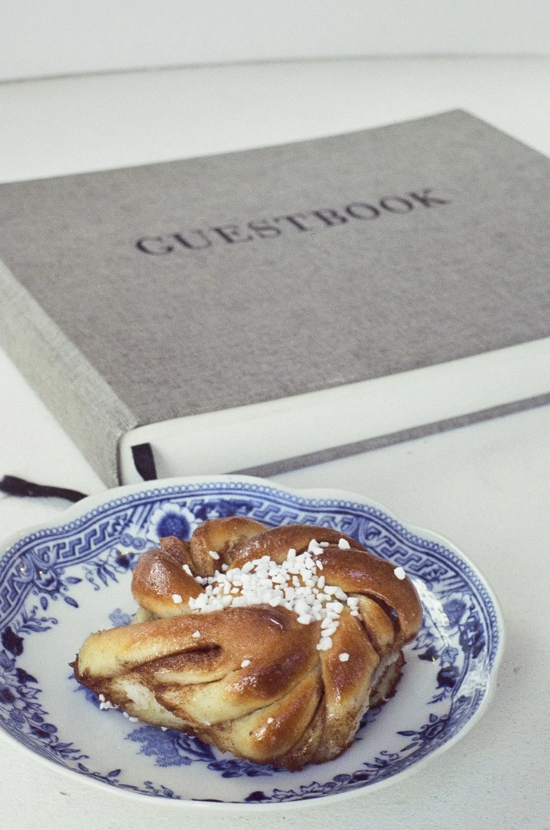 Un livre de cuisine britannique avec une croix anglaise bleue et blanche en dessous, un napolitain et un grand livre intitulé 'GUESTBOOK'