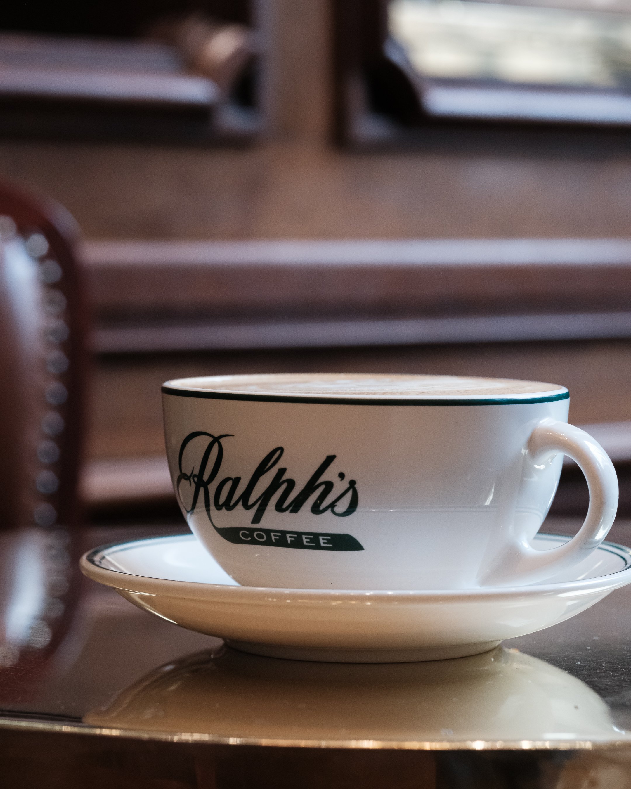 Photographie prise au Ralph's Café à Paris, mettant en avant l'identité visuelle forte de l'enseigne au premier plan et l'atmosphère du lieu au second plan. 