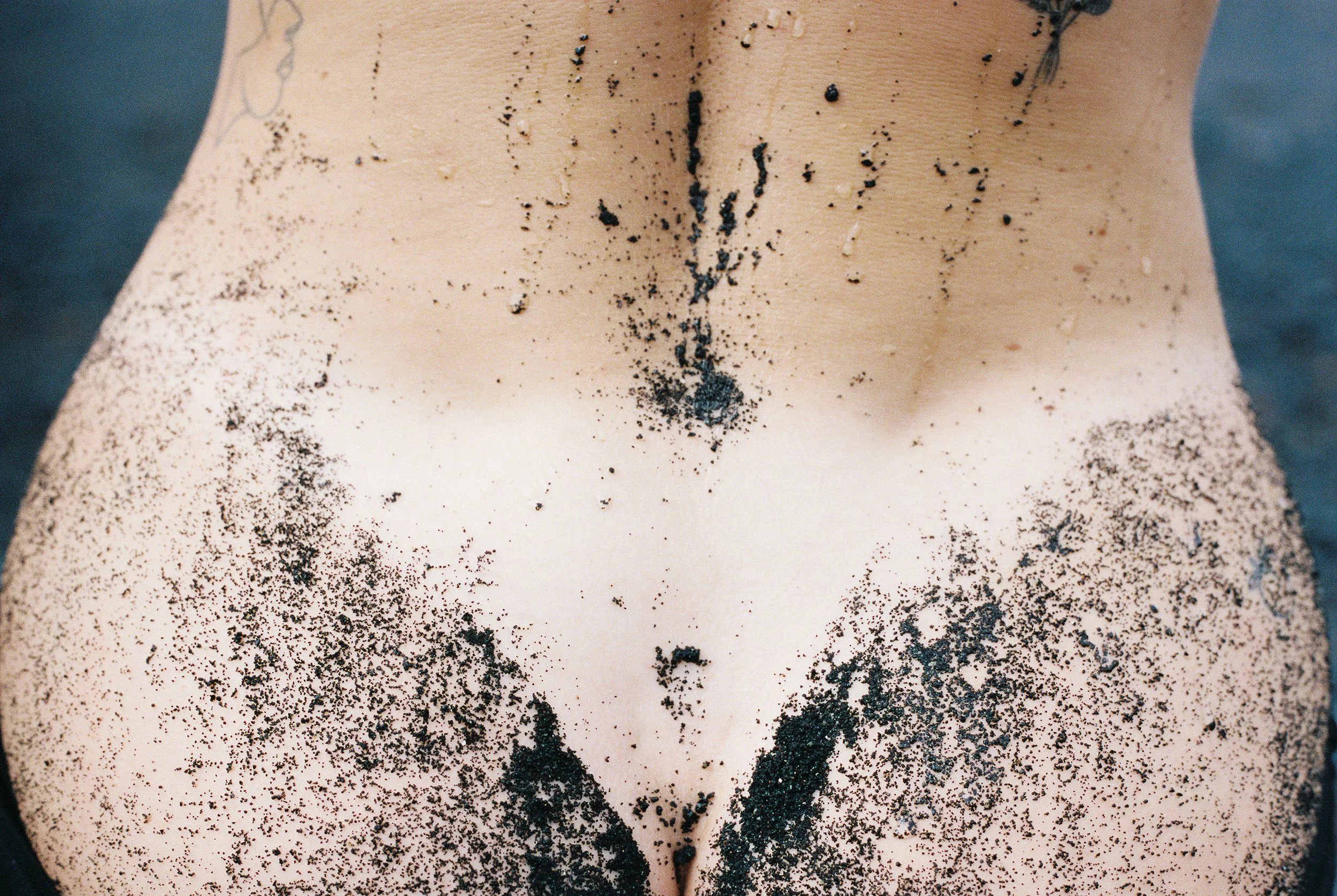 Photo of a female body showing her back, her butt and a sunbathing mark. Photo taken in Lanzarote (Canary Islands) on a black sand beach. 
Film photo, 35mm Kodak Portra 400, Olympus OM-2. 