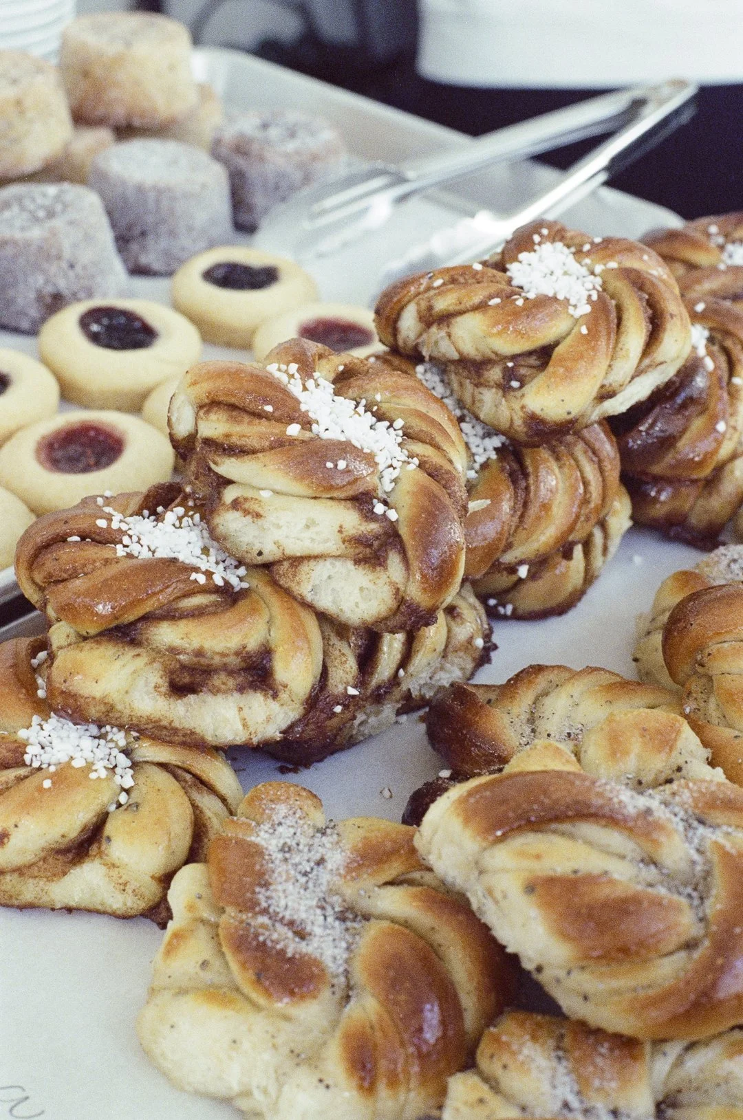 Gâteaux et biscuits sucrés, certains agrémentés de sucre perlé ou de confiture, sont exposés sur un plateau.