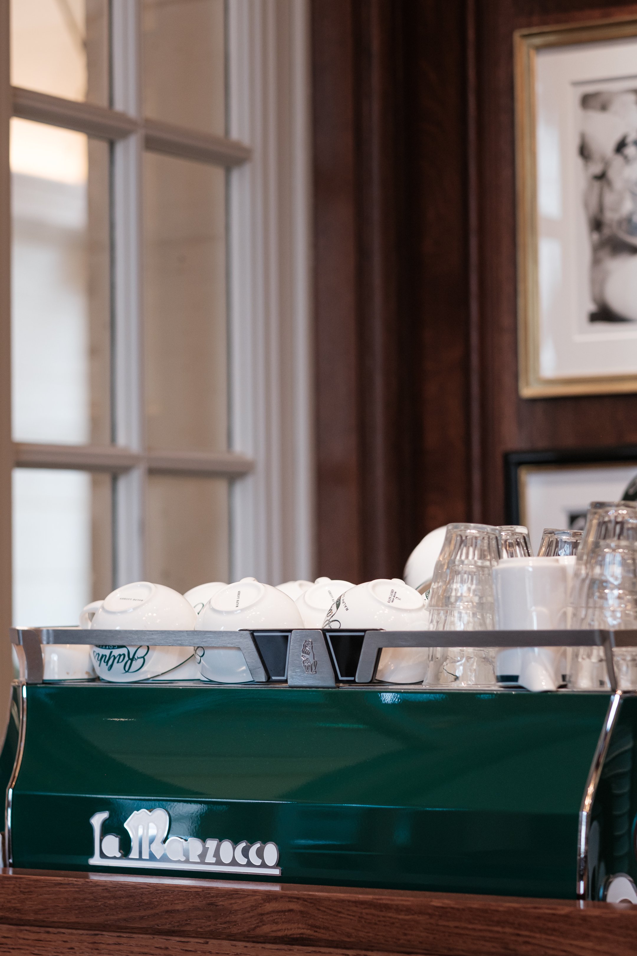 Photographie prise au Ralph's Café à Paris, montrant la machine à café utilisée et les couleurs choisies pour l'identité visuelle de la marque à l'international. 
