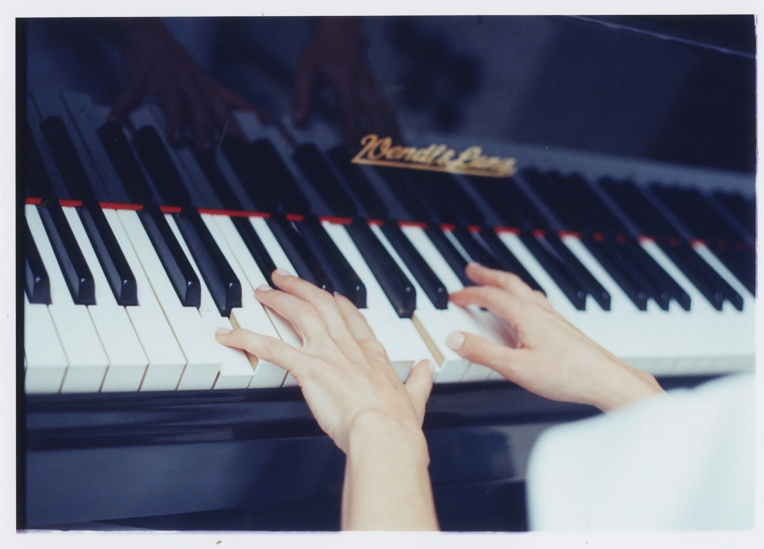 Photo of a bride on her wedding day playing the piano. The chosen film increases that blue ambiance and softens the colors, as it's a film that's used for cinema. We can see her hands moving as she's playing the piano.
Photo taken in a luxurious hote