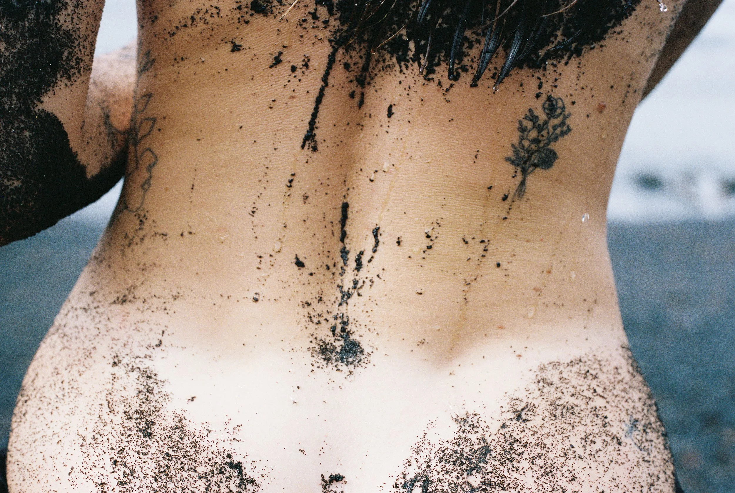 Photo of a female body showing her back, her butt and a sunbathing mark. Photo taken in Lanzarote (Canary Islands) on a black sand beach. 
Film photo, 35mm Kodak Portra 400, Olympus OM-2. 