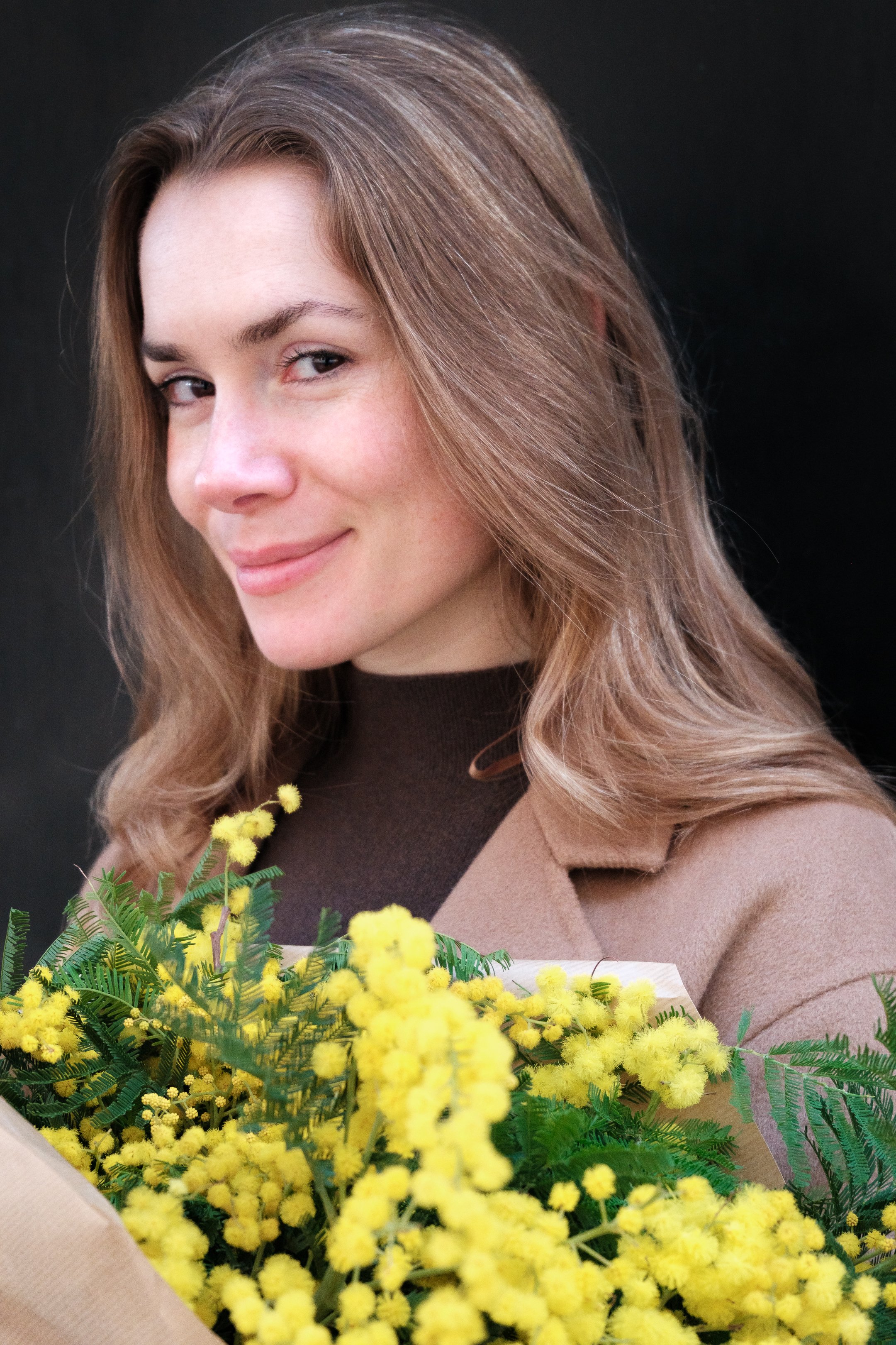 Photographie prise dans les rues de Paris montrant les détails des conditions extérieures (luminosité forte, ombres) et la palette de couleurs harmonieuse. Le mimosa apporte de la douceur à la mannequin. 