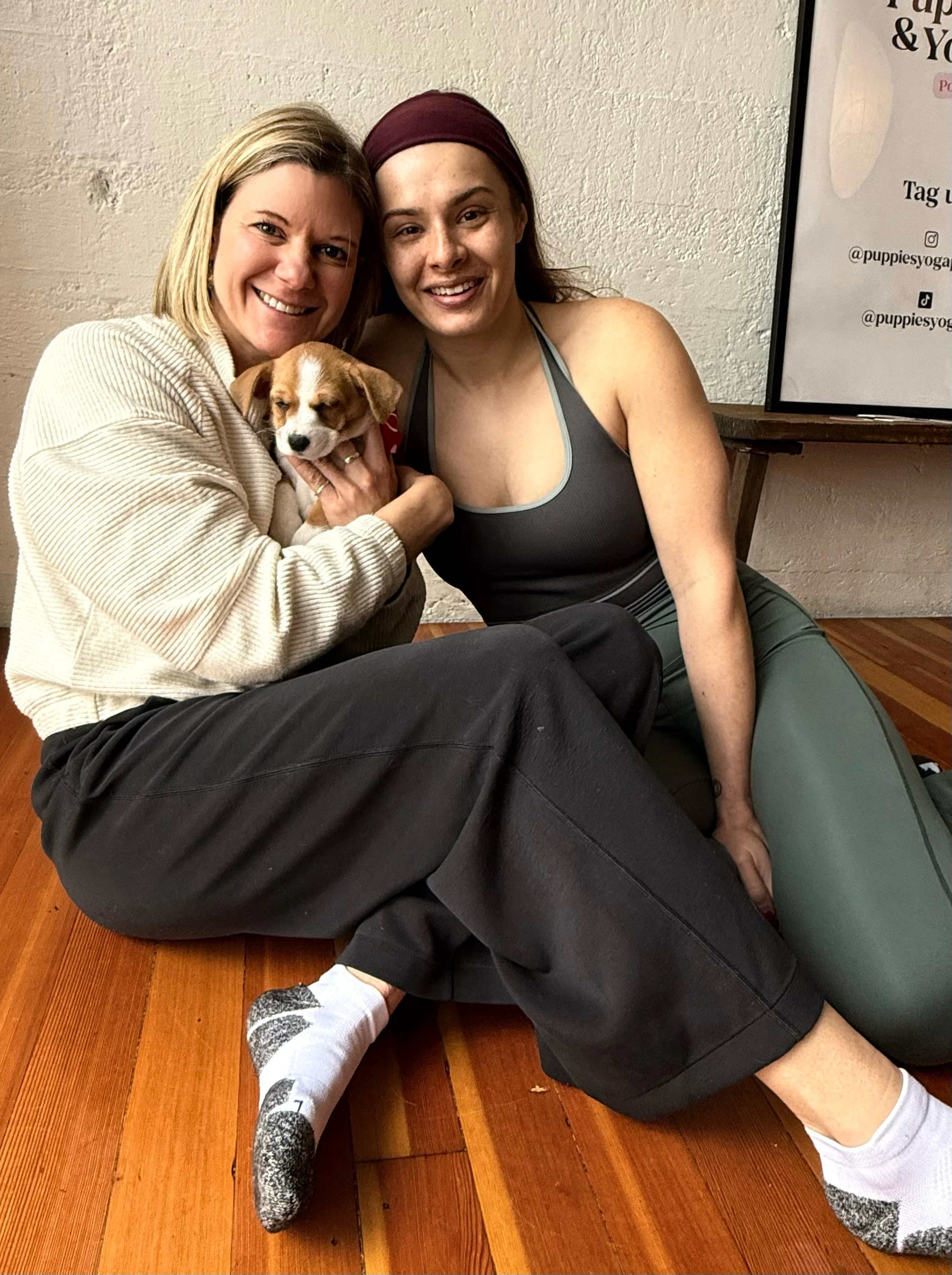 Clients and friends posing with puppies at Puppy Yoga 2026, a VIP client appreciation event hosted by Rhonda Riley in Portland, OR