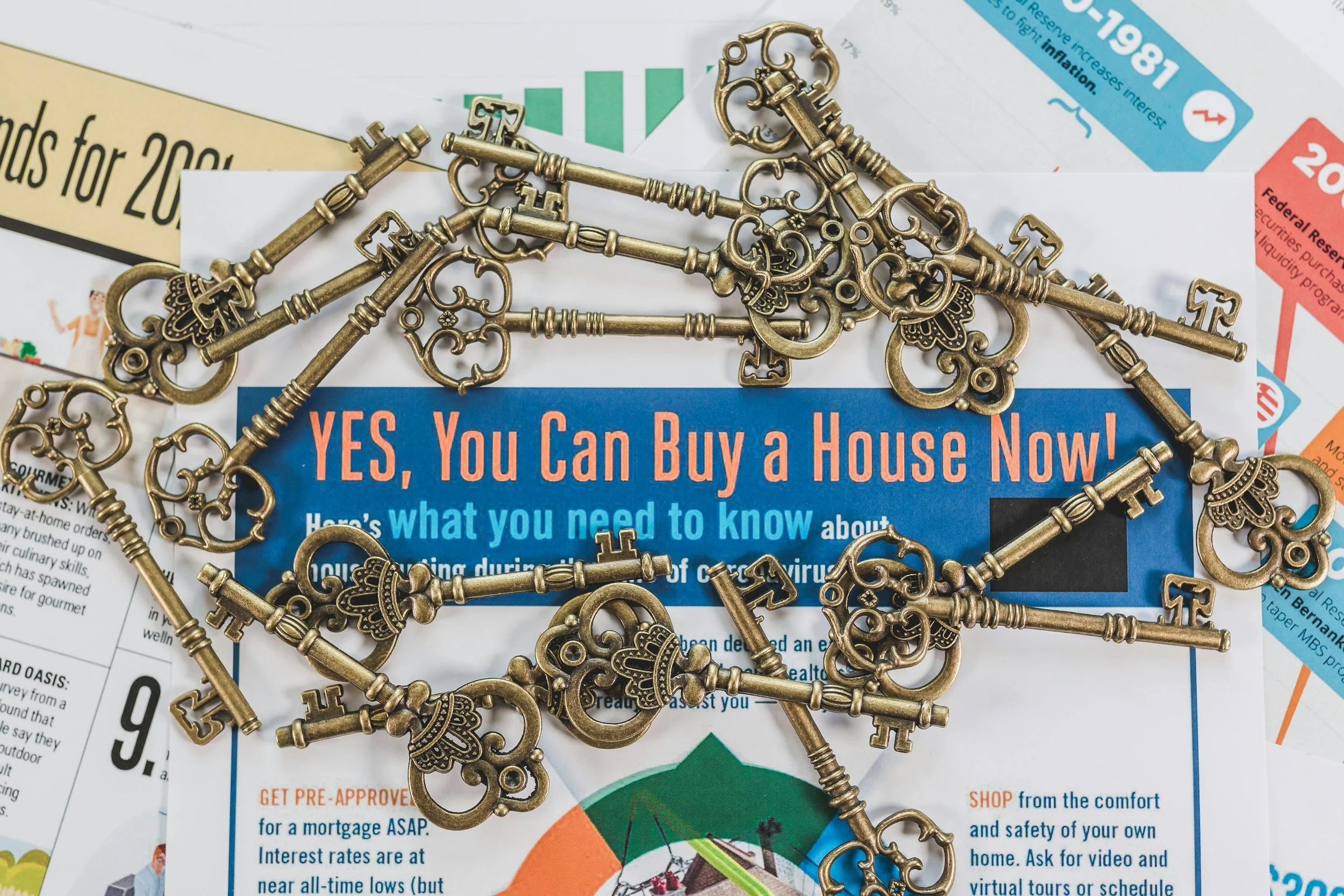 Multiple ornate antique brass keys scattered over a real estate flyer titled 'YES, You Can Buy a House Now!', representing the various paths and opportunities in the Forest Grove housing market.