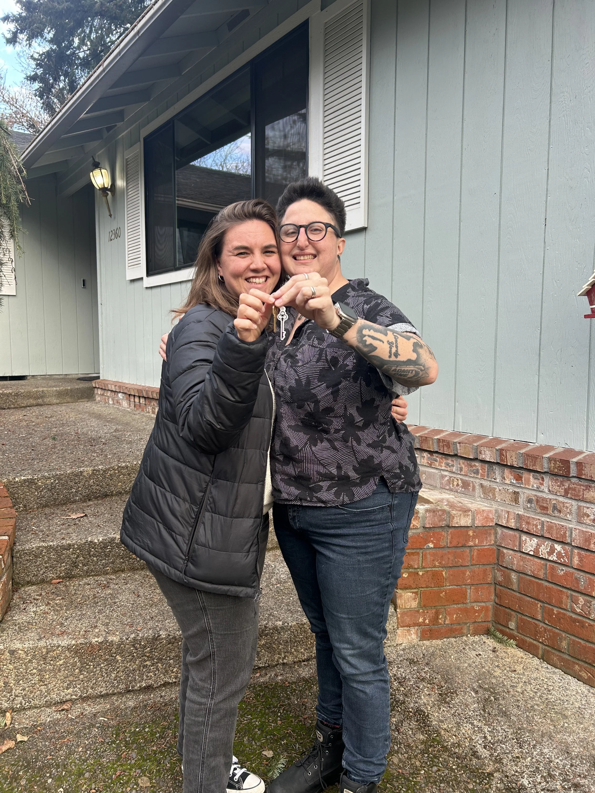 Rhonda Riley clients holding keys in front of their new house, they are new homeowners in Portland