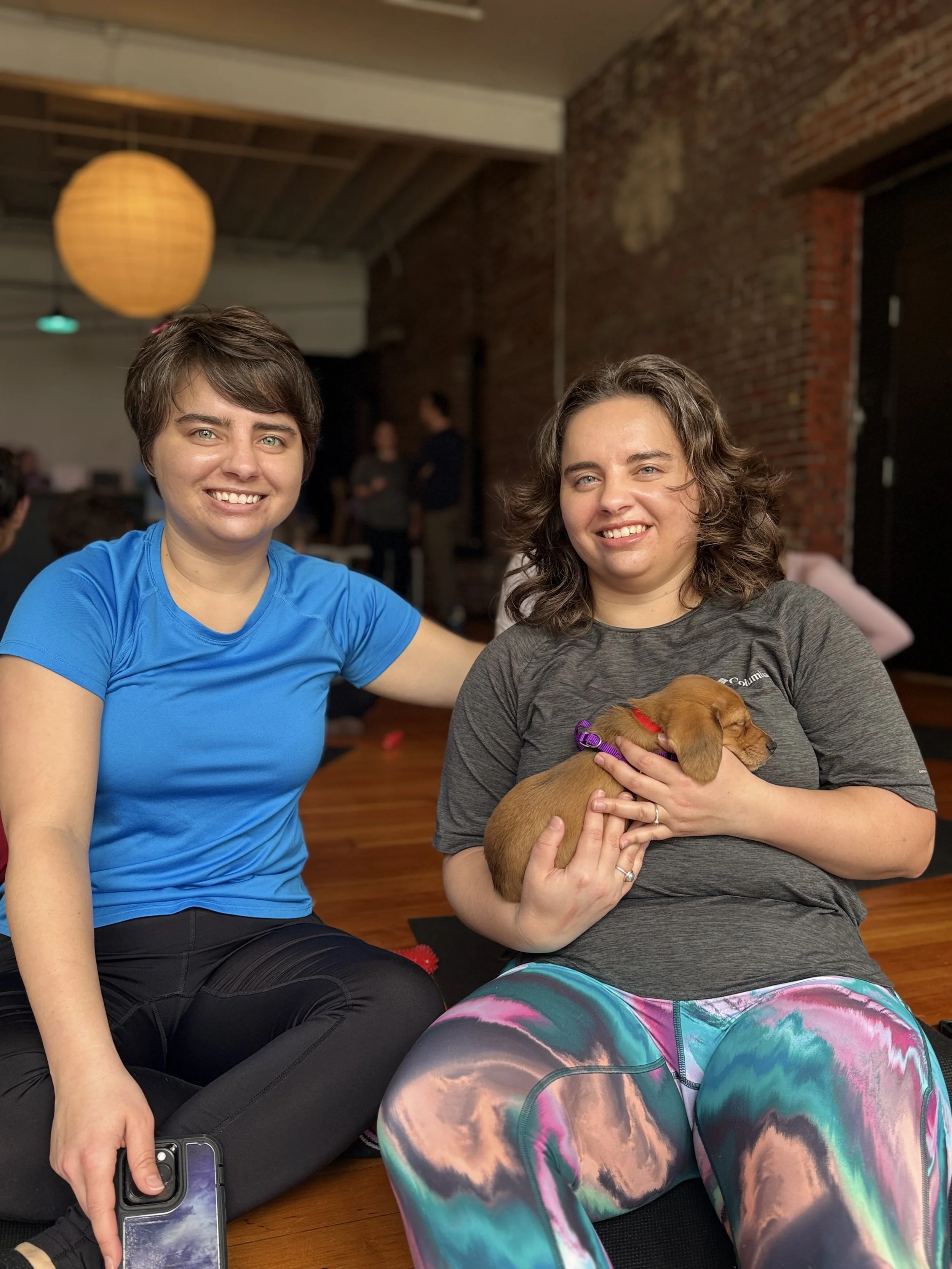 VIP clients and referrals laughing and playing with puppies during Puppy Yoga 2026 in Portland, OR