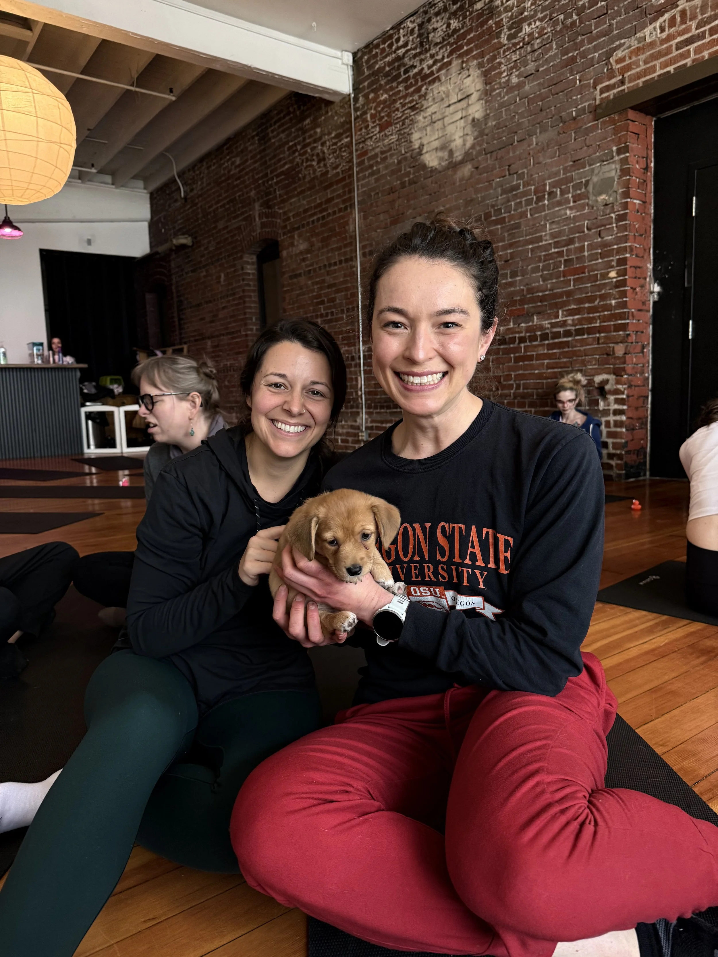 VIP clients and friends posing with puppies and Rhonda Riley at Puppy Yoga 2026 in Portland, OR