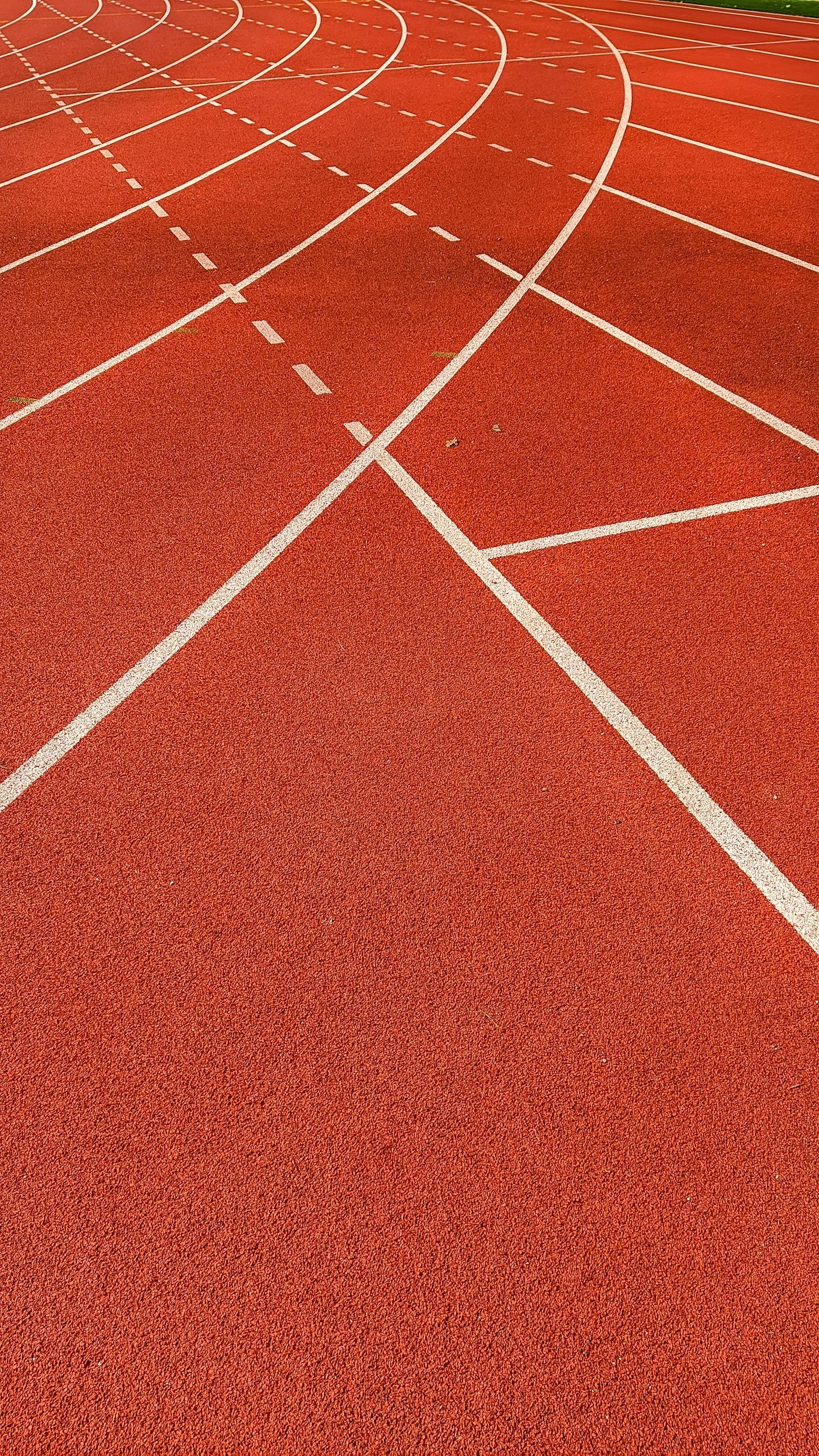 Red running track with white lane markings and curved lines.