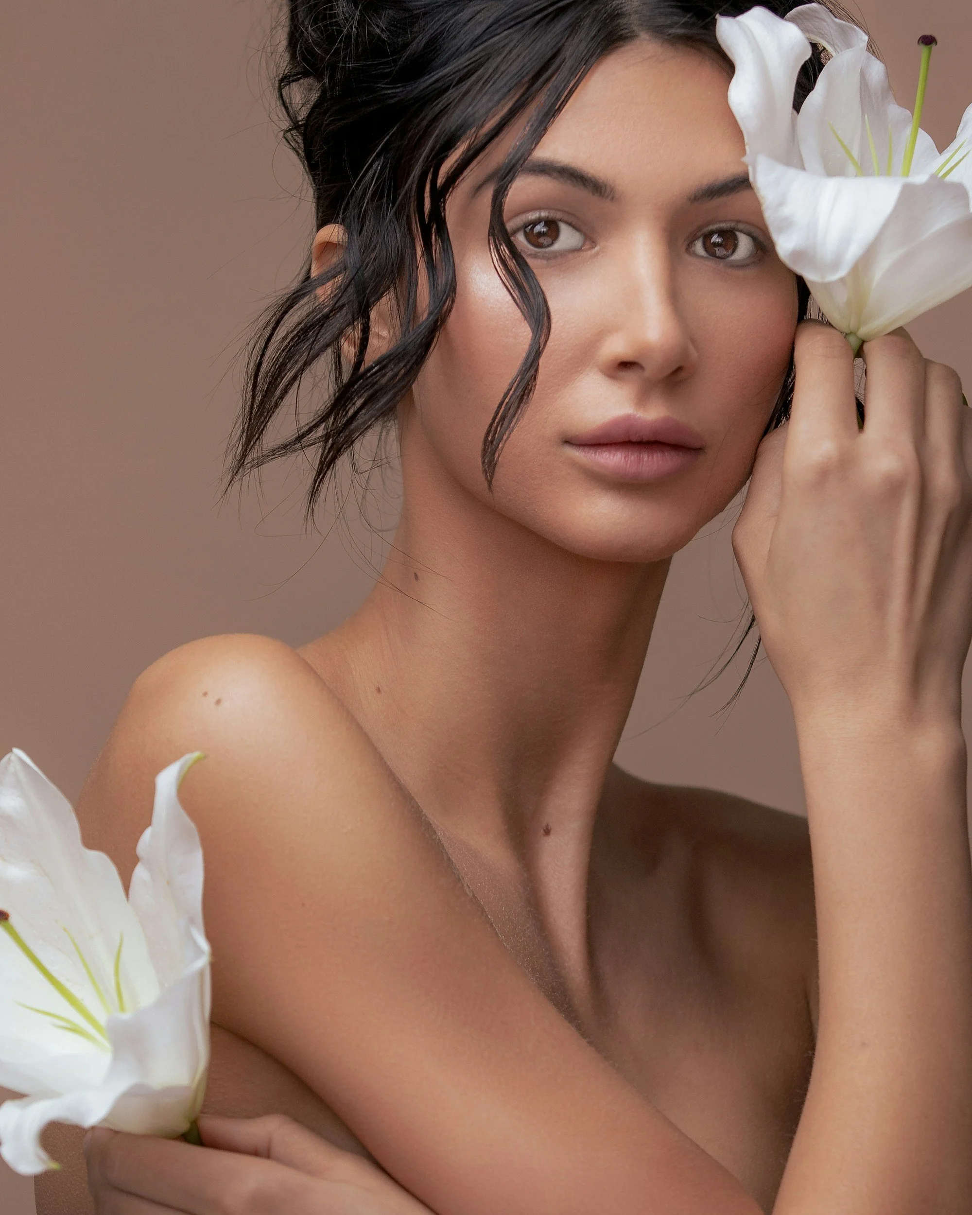 Natural portrait of a woman with white lilies, highlighting healthy skin and a soft botanical aesthetic.