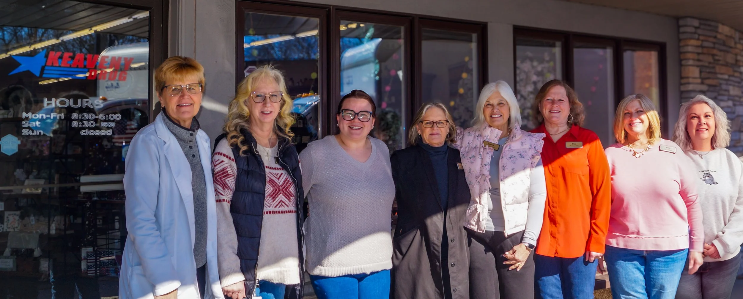 Group of women standing outside a store, smiling for the photo.
