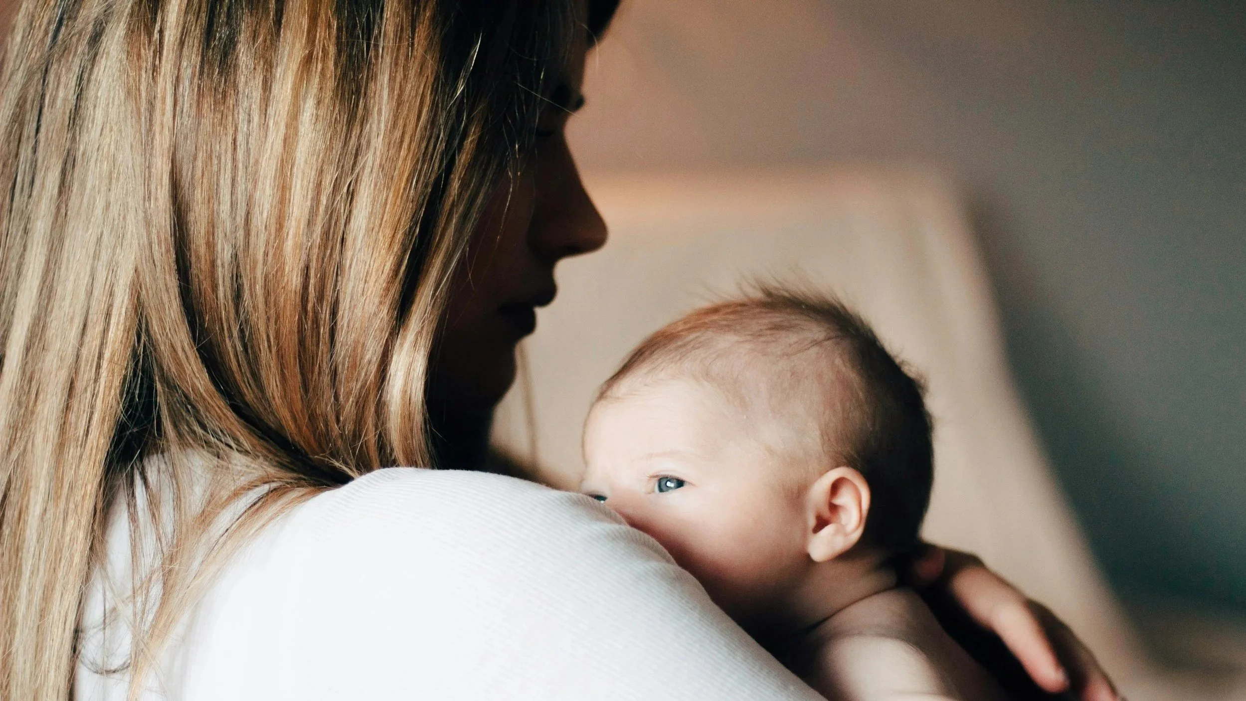 Mother holding a newborn baby close, capturing early postpartum bonding alongside the emotional vulnerability and anxiety many women experience after childbirth