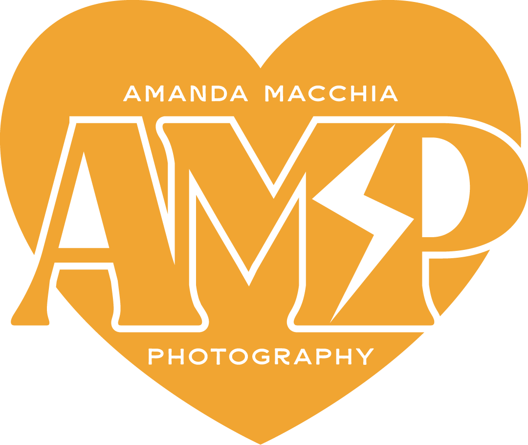 A logo for Amanda Macchia Photography featuring a yellow heart with black outline and text, including a lightning bolt inside the letter M.