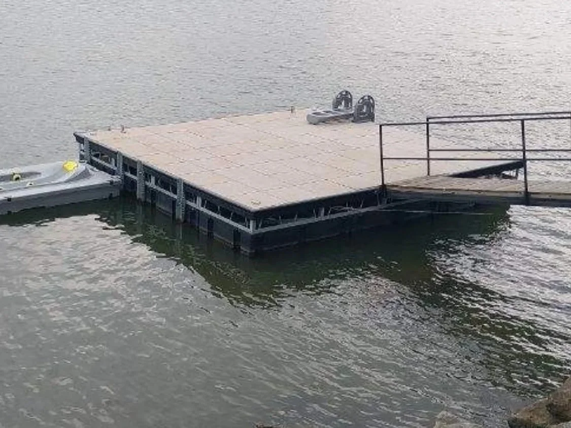 A floating dock on a body of water with two boat lifts attached to it.
