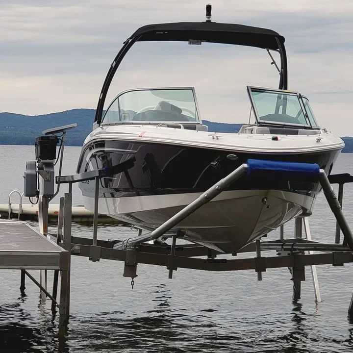 A motorboat on a dock, with a body of water and hills in the background.