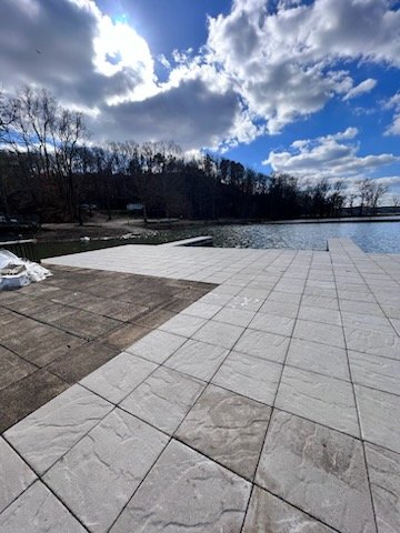 Outdoor lake area with Shoreline surface under a partly cloudy sky, surrounded by leafless trees.