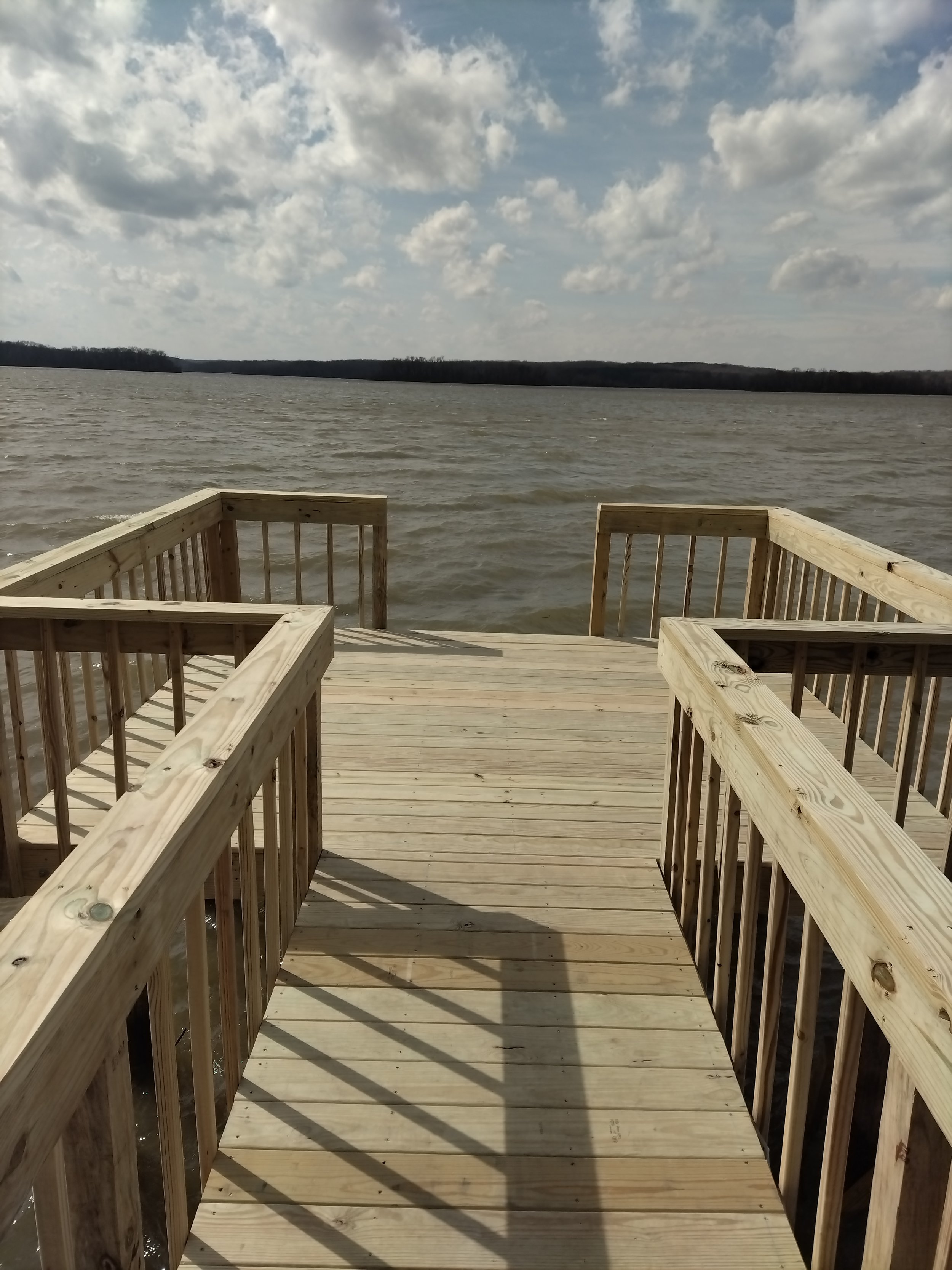 Wooden dock extending over a body of water, with a cloudy sky overhead.