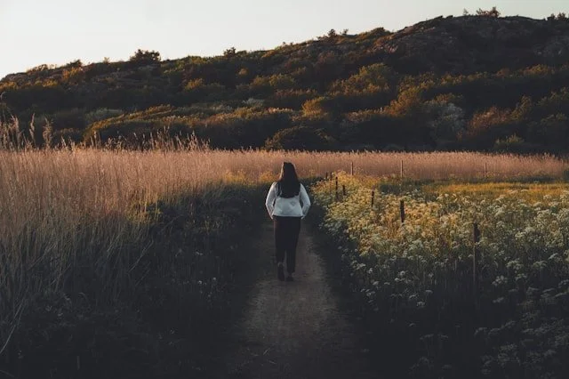 A woman walking in the countryside at sunset.