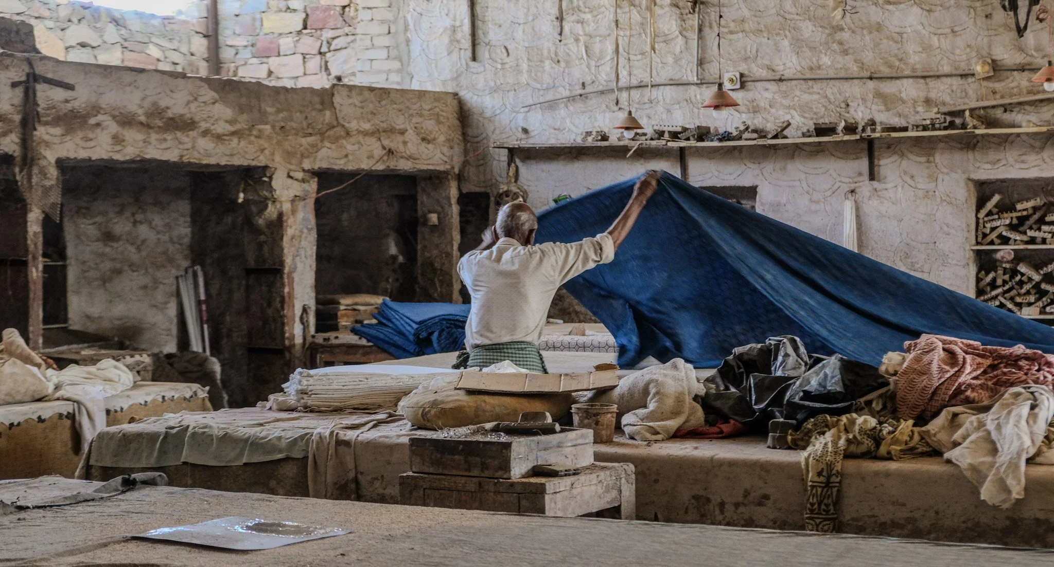 Artisan lifting indigo-dyed cloth in preparation for block printing in a traditional workshop in Pipar, Rajasthan