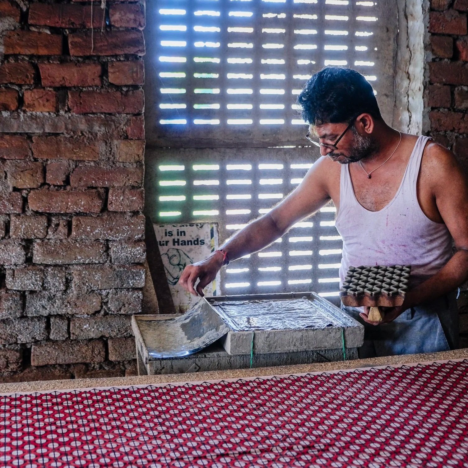 Block printer loading natural dye onto a printing pad in a traditional workshop in Bagru, Rajasthan
