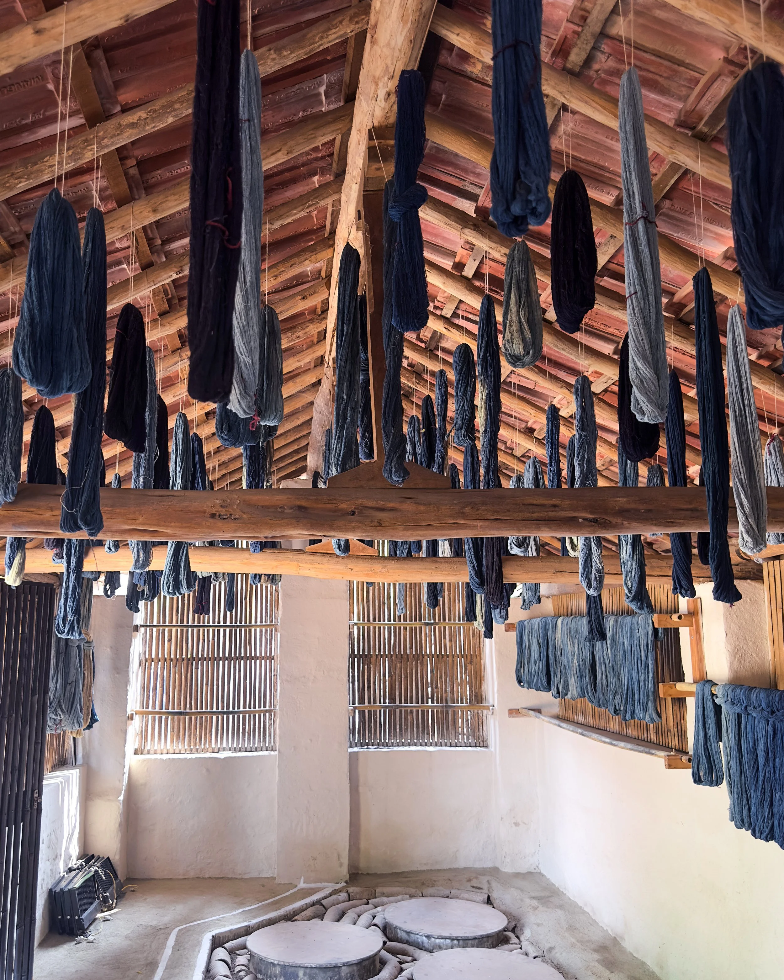 Indigo-dyed threads hanging to dry above stone dye vats in a traditional workshop in Bhuj, Kutch, Gujarat