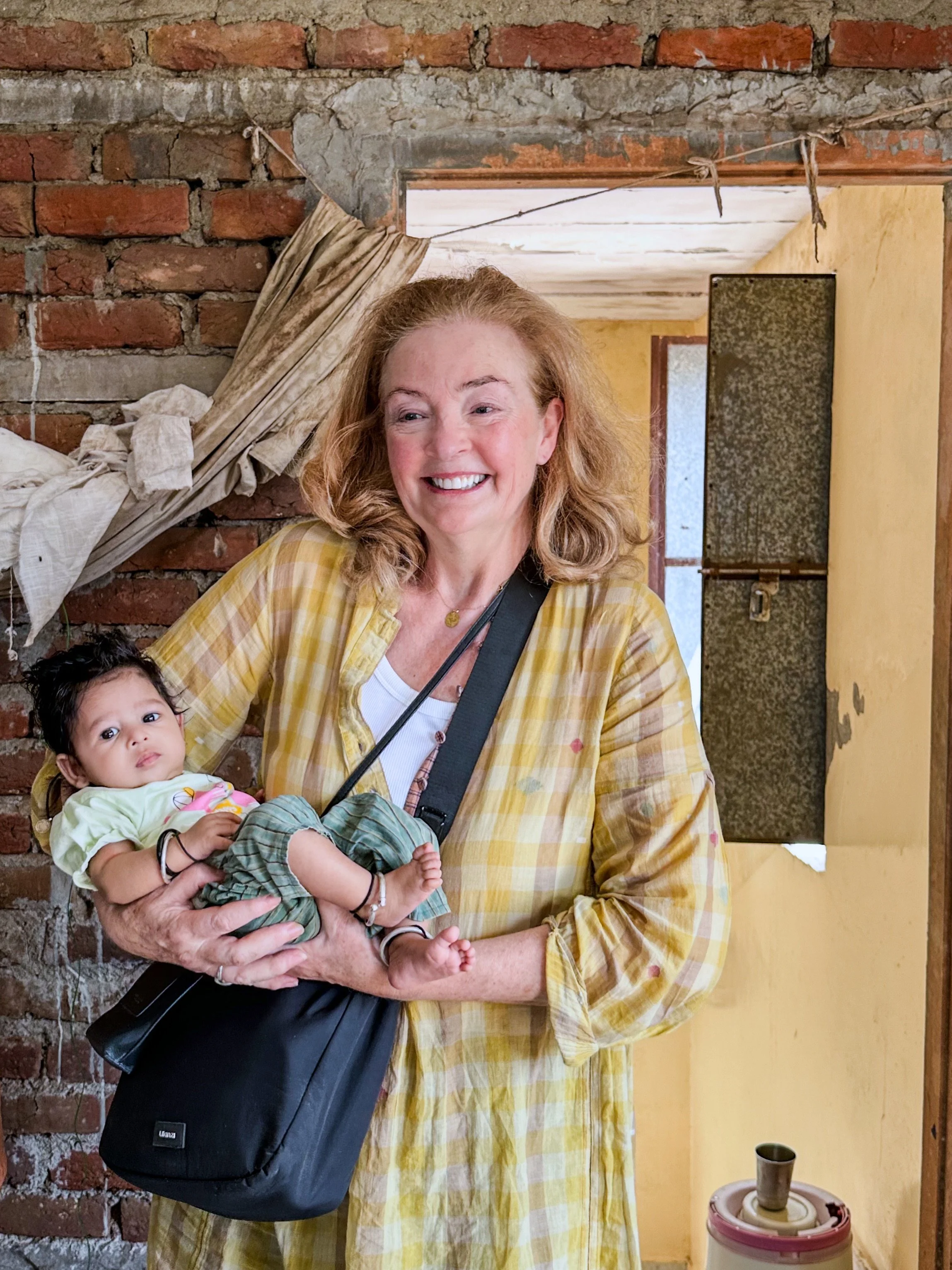 Bernadette O’Farrell holding a baby at a block print workshop in Bagru, Rajasthan