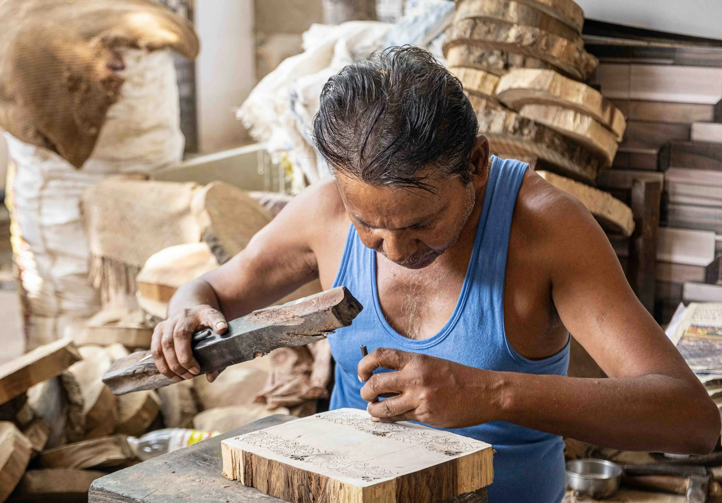 Artisan carving an intricate design into a wooden block for hand printing in Bagru, Rajasthan