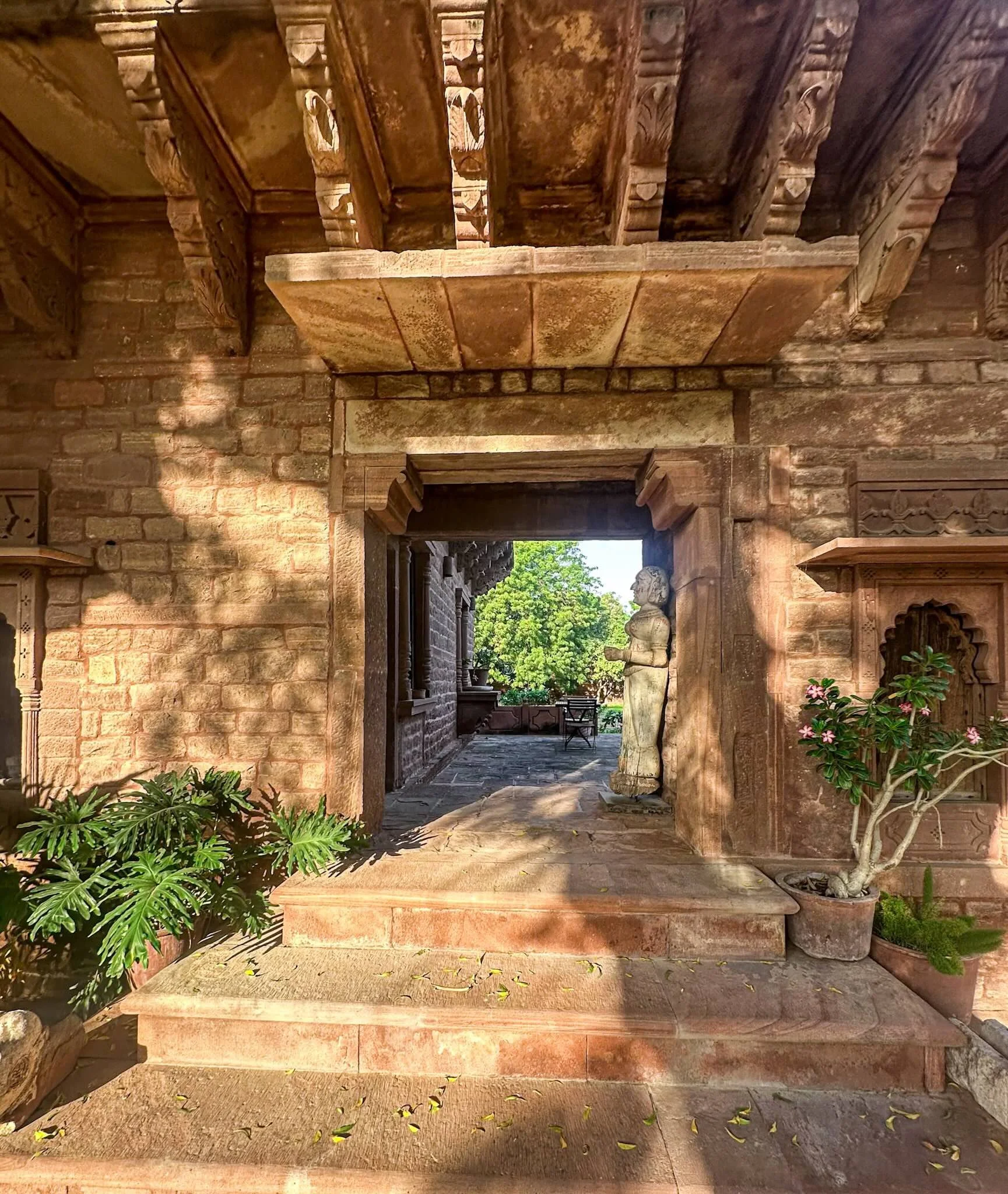 Garden doorway at Sukh Sagar Haveli with stone steps leading into a sunlit courtyard, Rajasthan